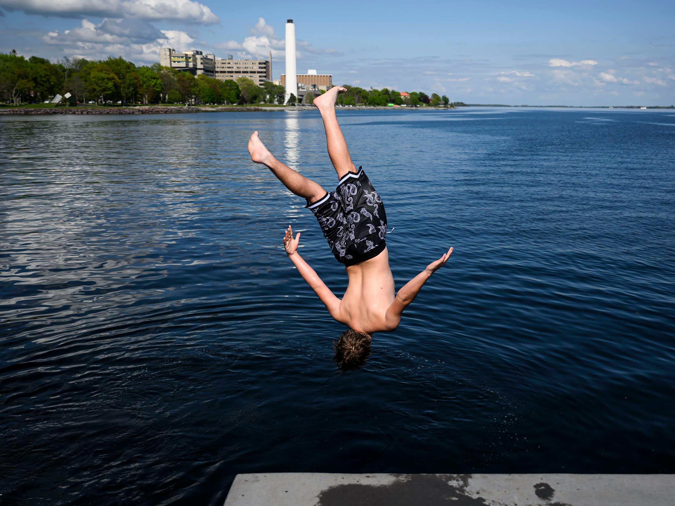 A boy jumps into a lake.