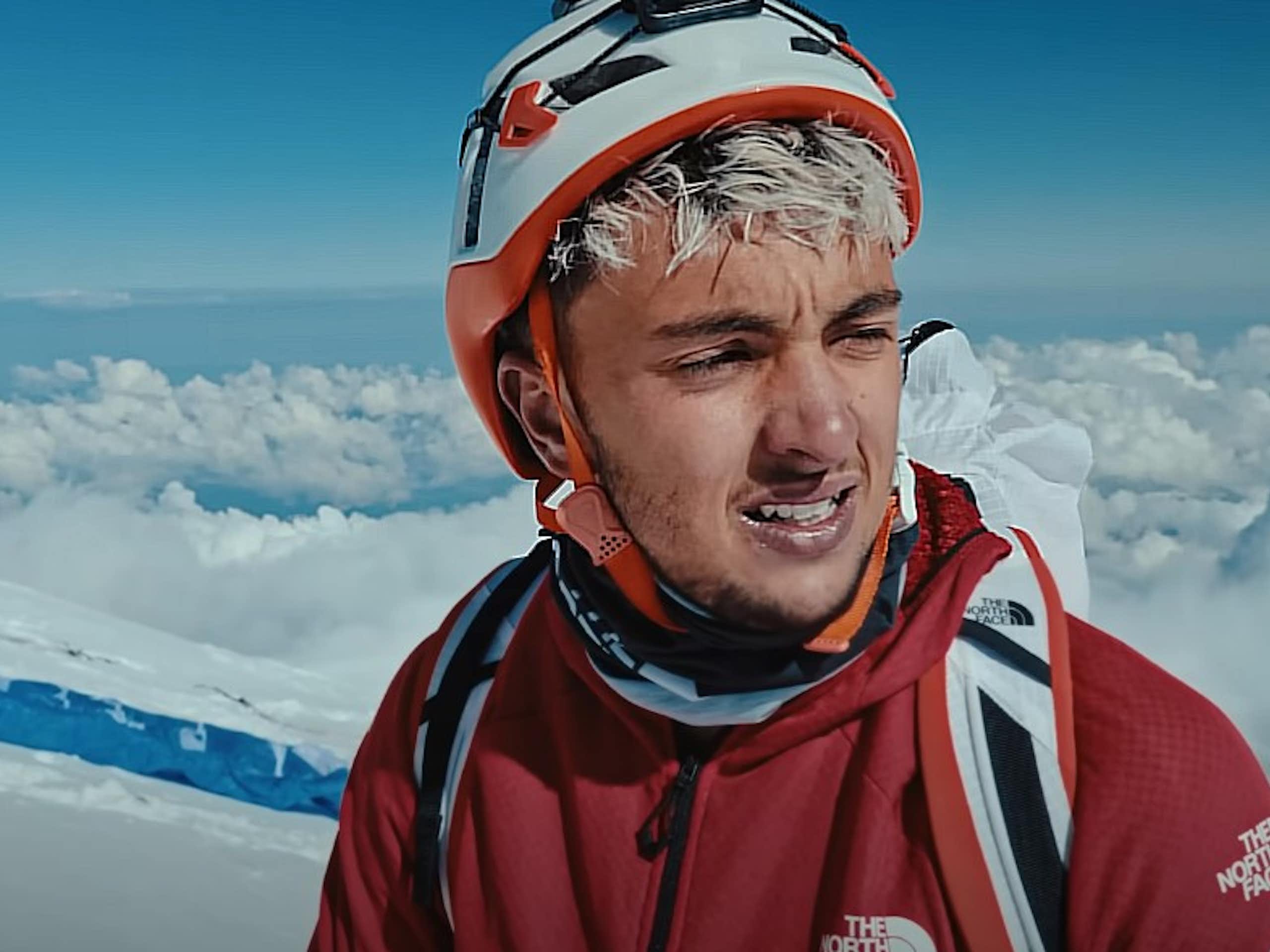 Un homme en tenue d'alpinisme se trouve en haute altitude.