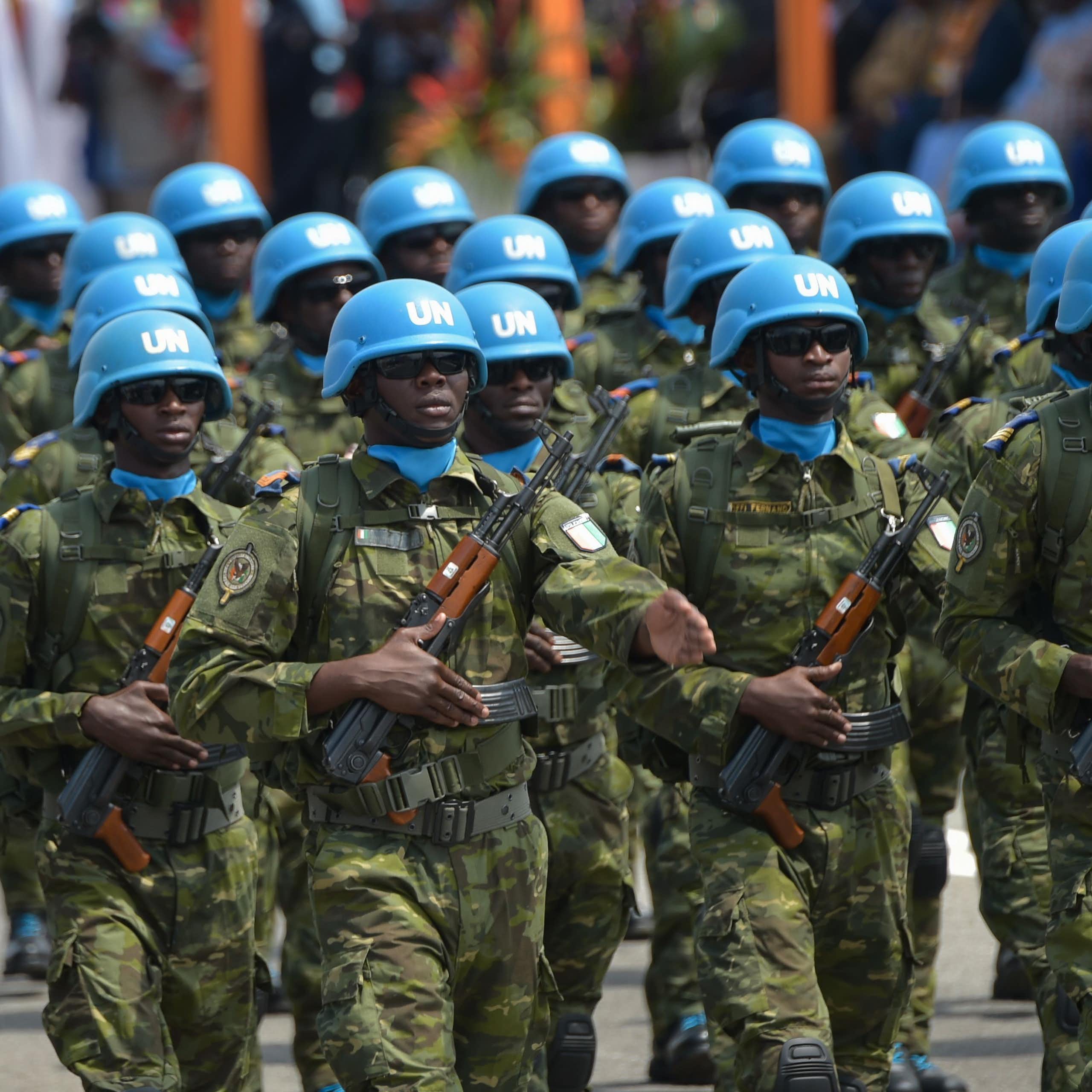 Soldiers wearing UN blue helmets and carrying AK 47s march. 
