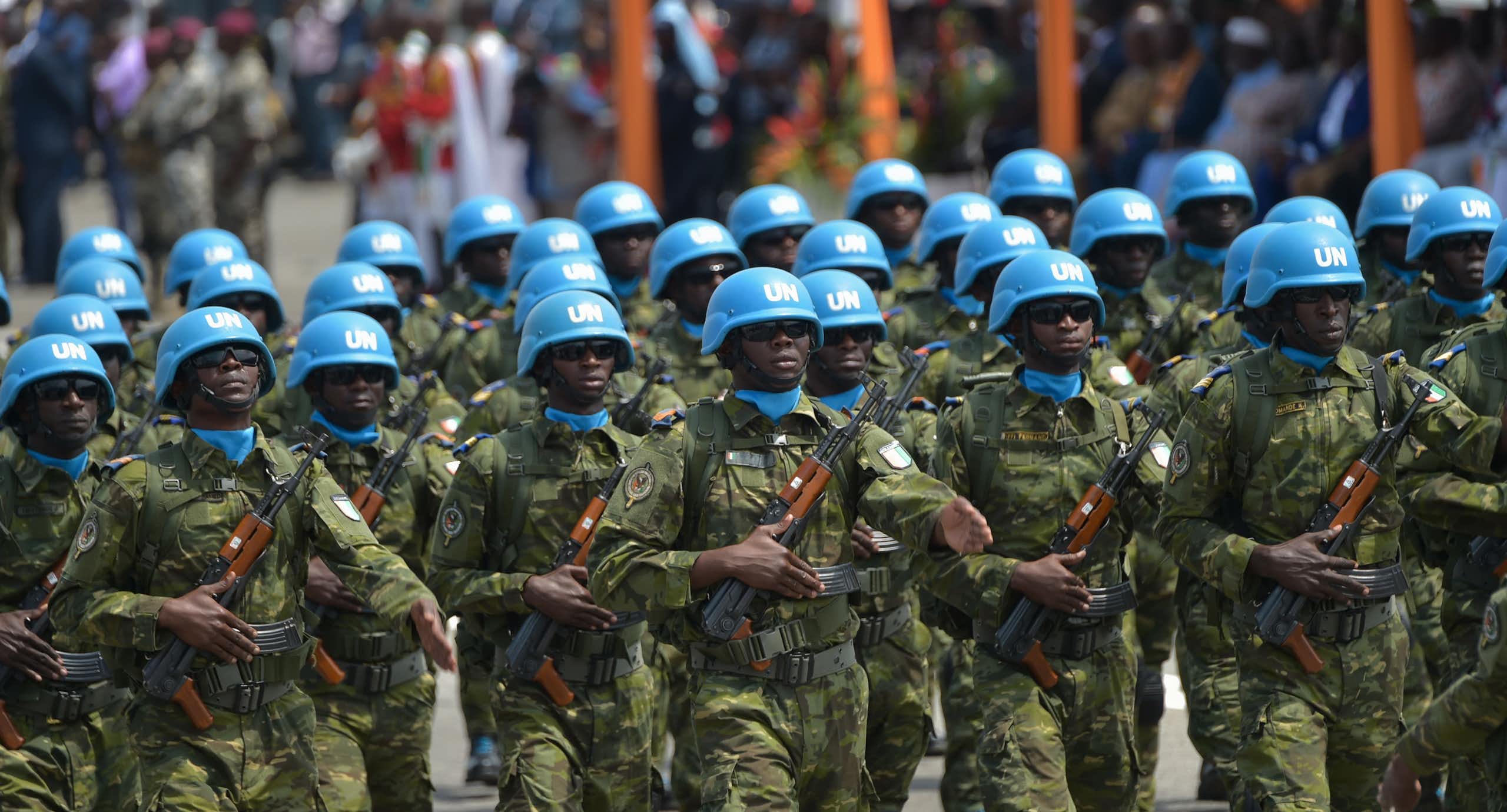 Soldiers wearing UN blue helmets and carrying AK 47s march. 