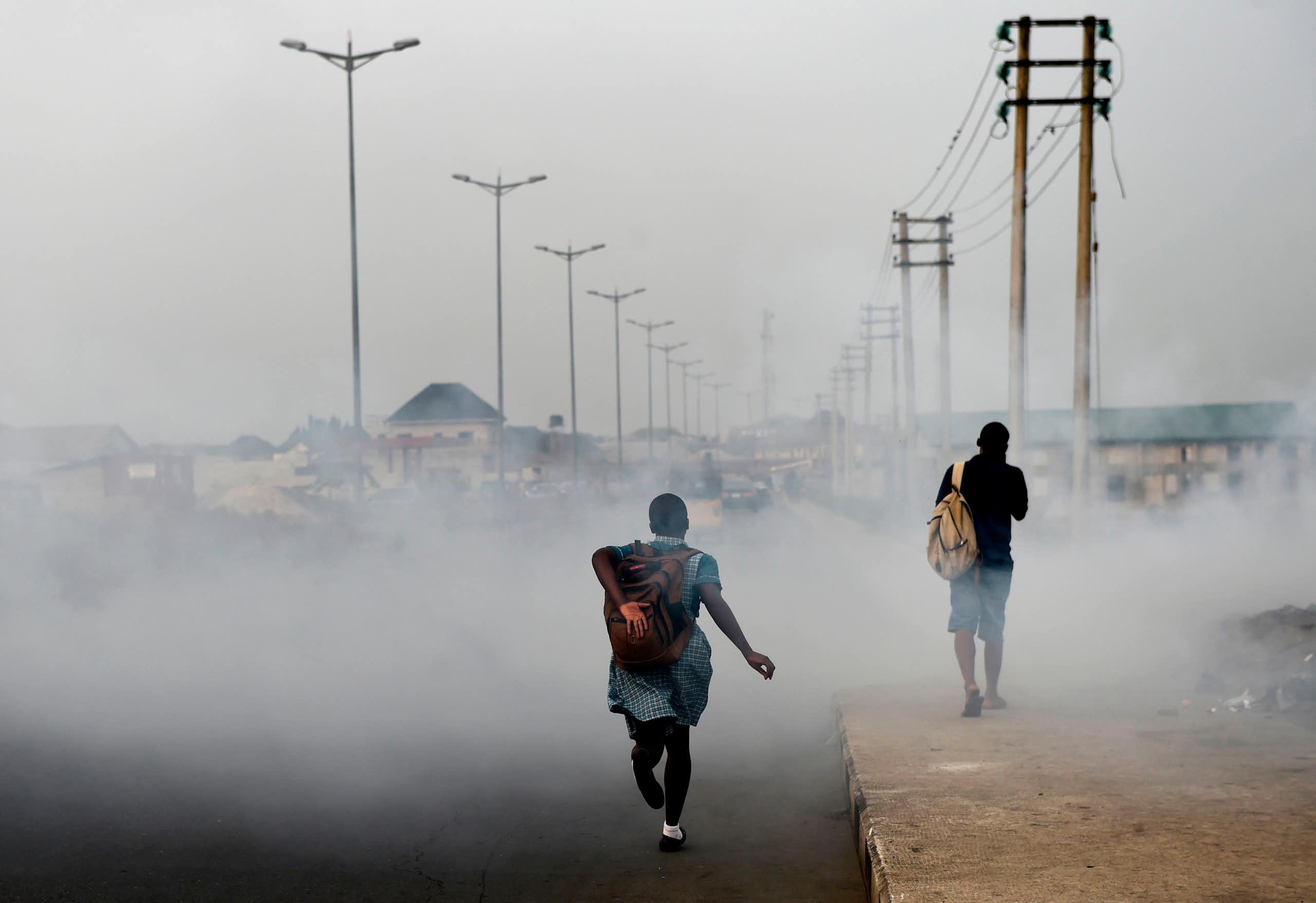 Girl walking down road filled with smoke 