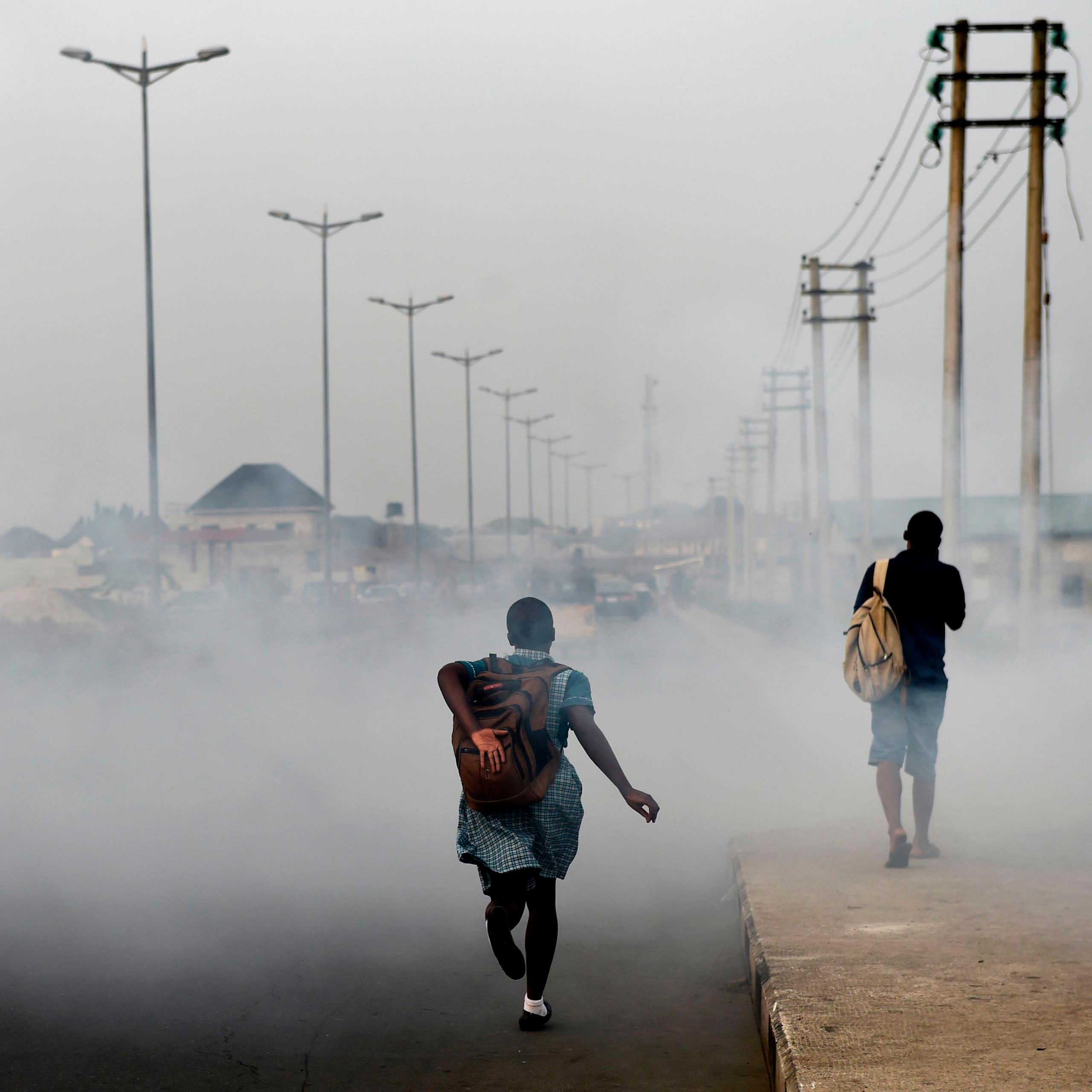 Girl walking down road filled with smoke 