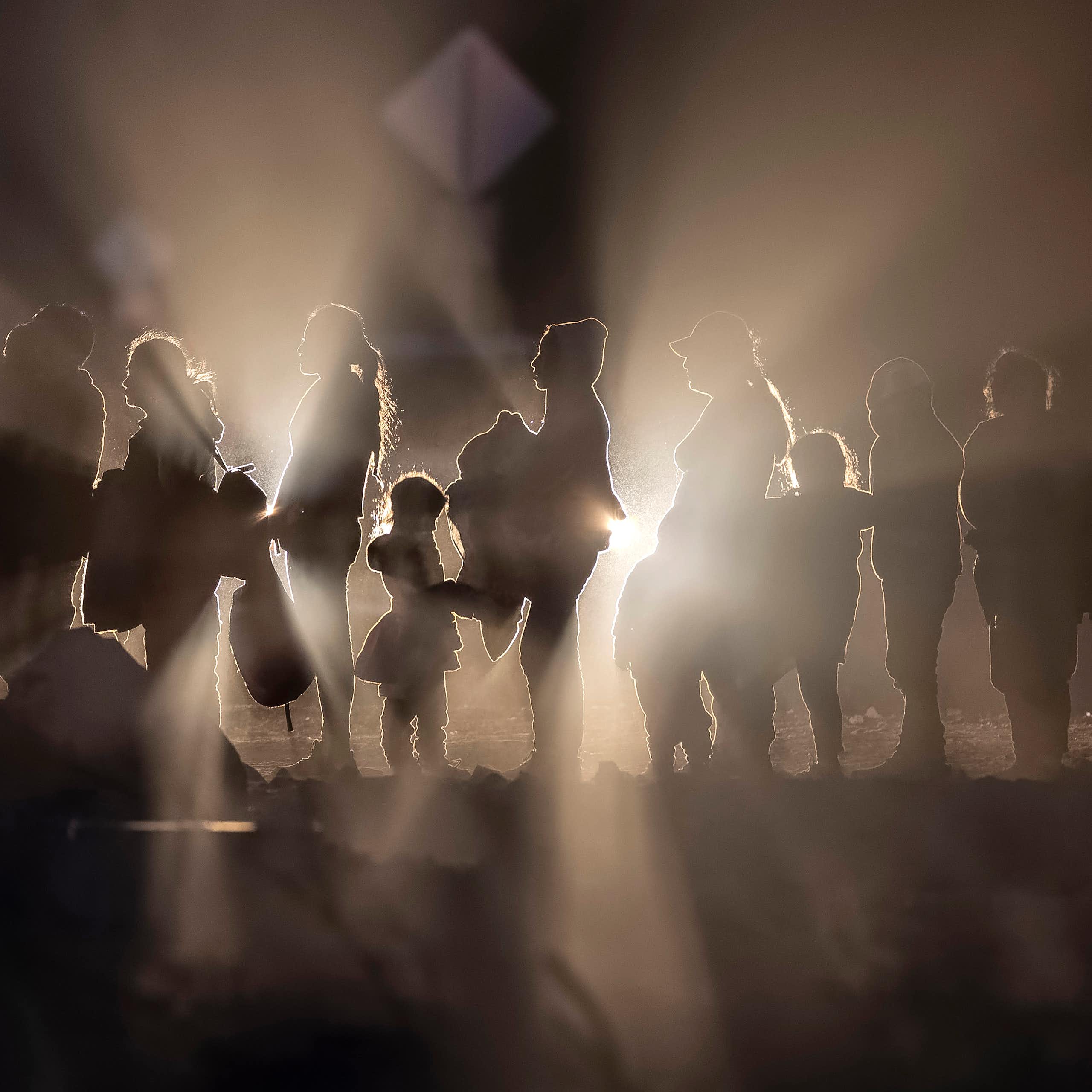 Immigrants, illuminated by car lights, form a line on the U.S.-Mexico border.