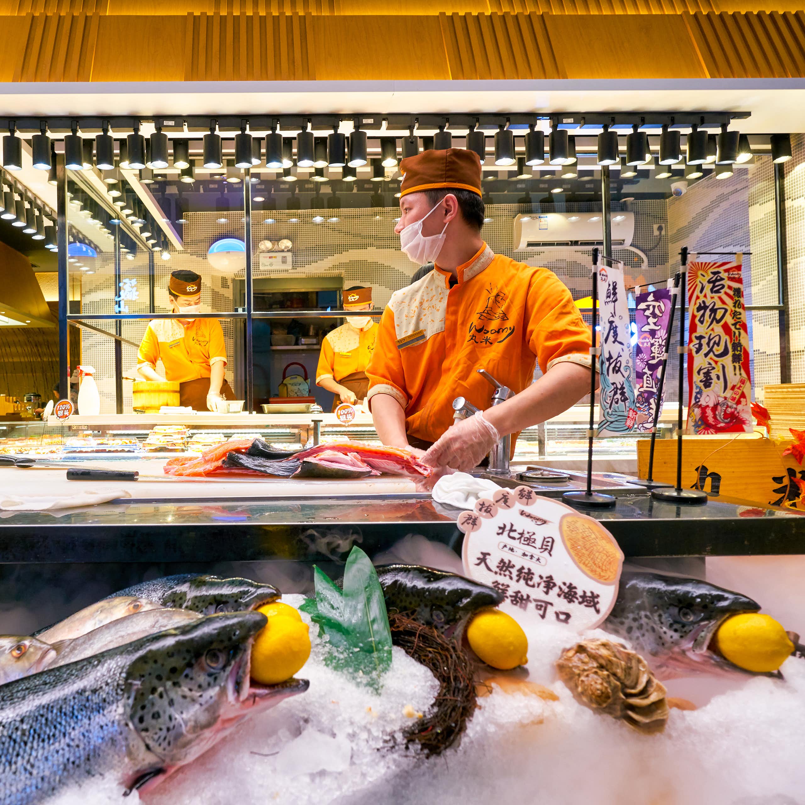 chinese chef preparing salmon in a restaurant kitchen
