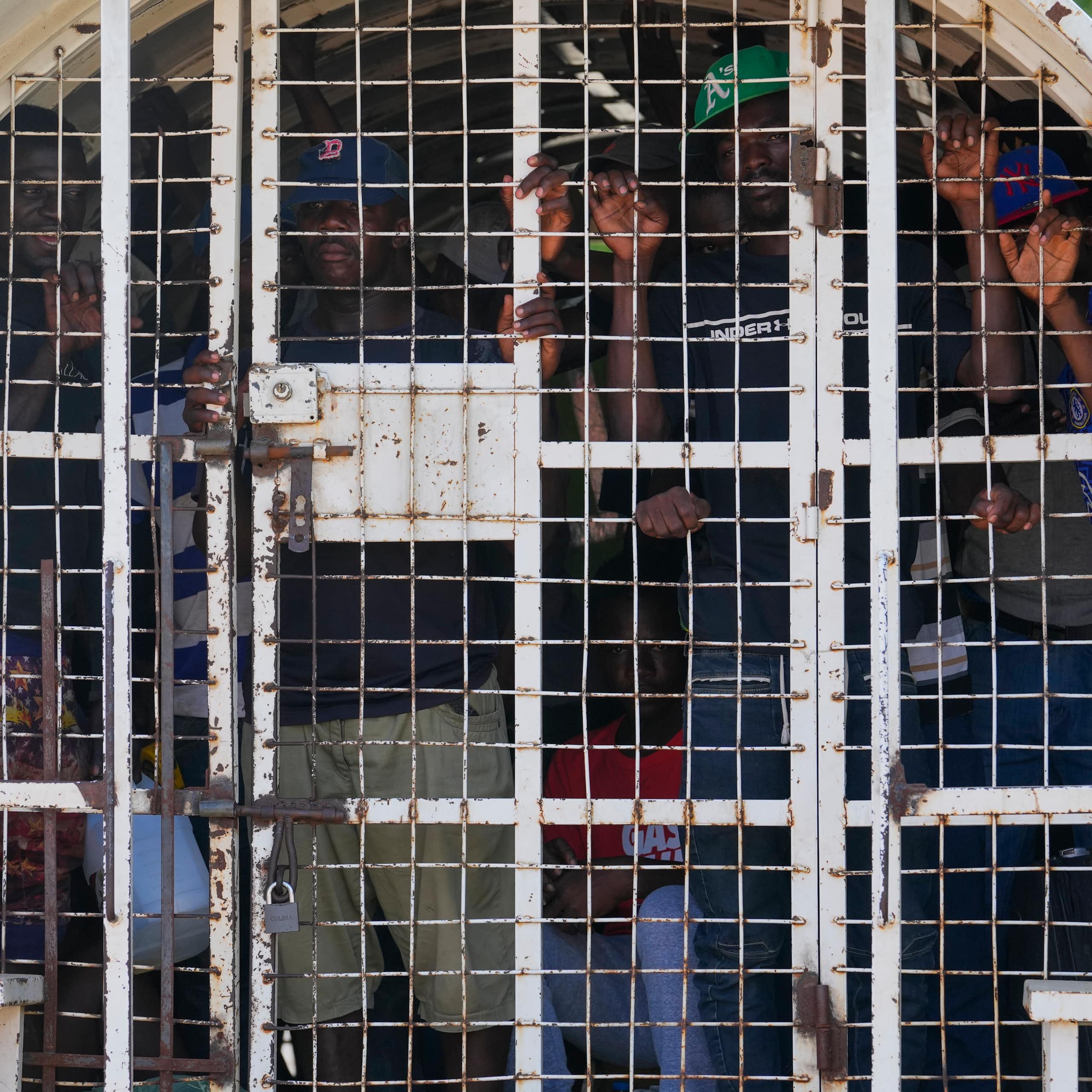 Des personnes noires à l'intérieur d'un véhicule de police en cage.