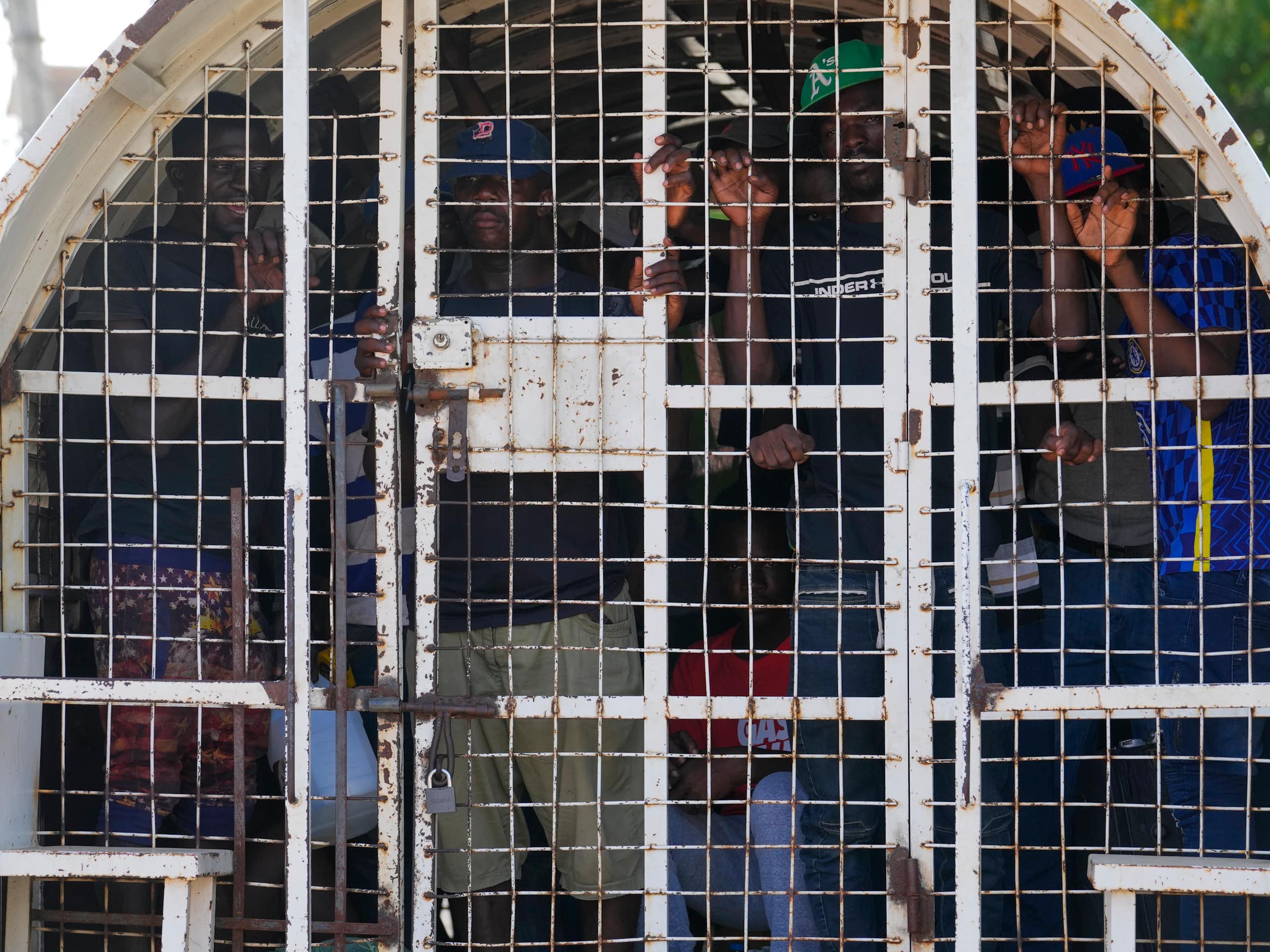 Black people inside a caged police vehicle.