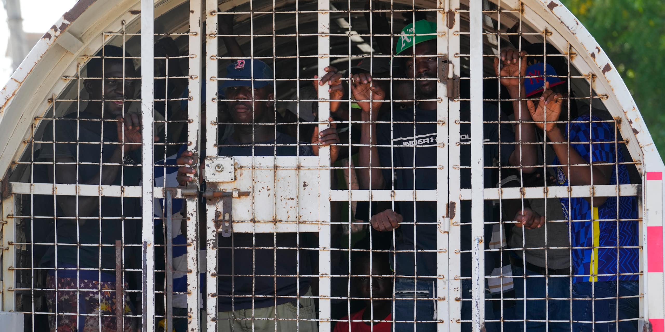 Des personnes noires à l'intérieur d'un véhicule de police en cage.