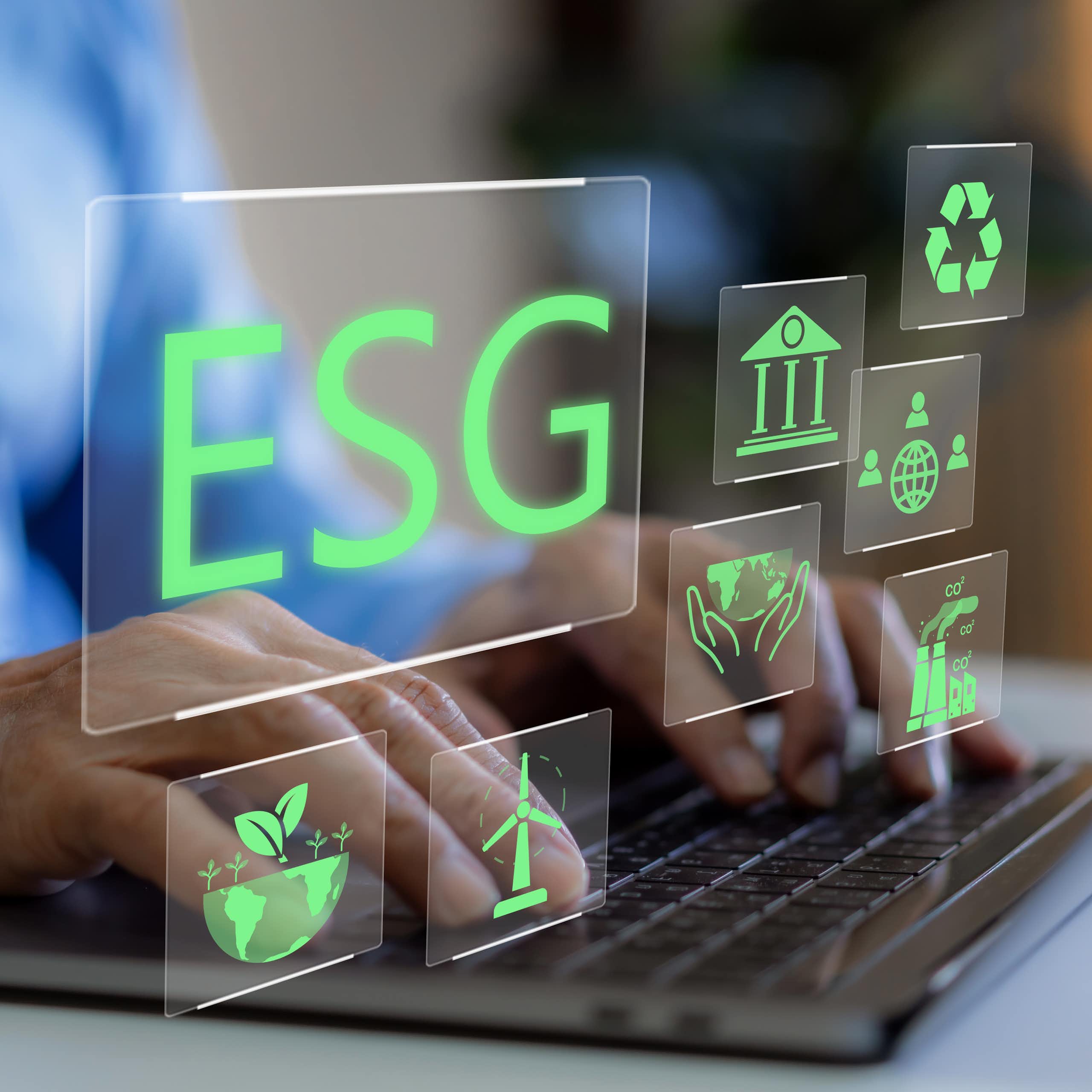 Pair of hands typing on a computer keyboard with green text that says ESG floats above