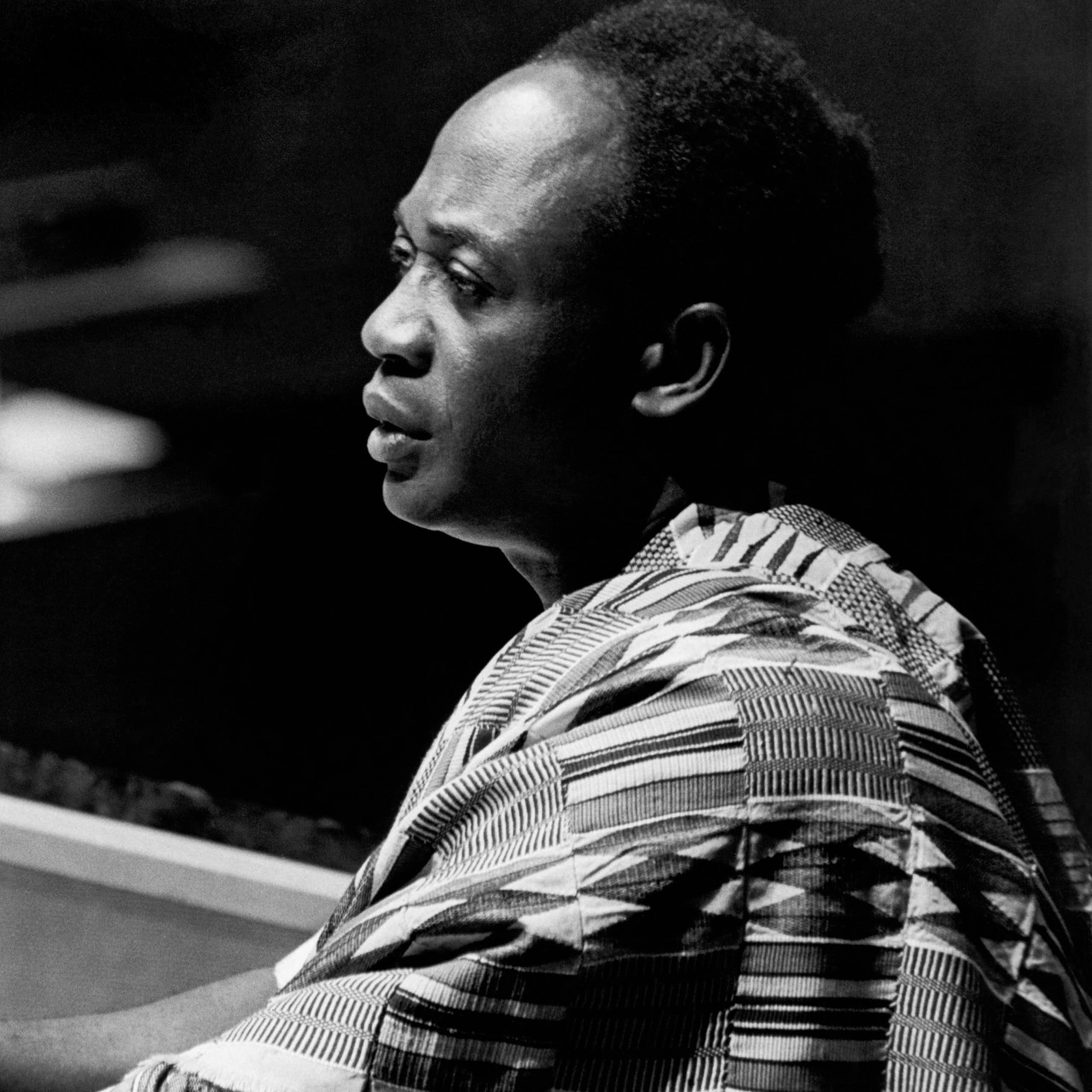 A man wearing Ghanaian traditional attire speaks at a podium.