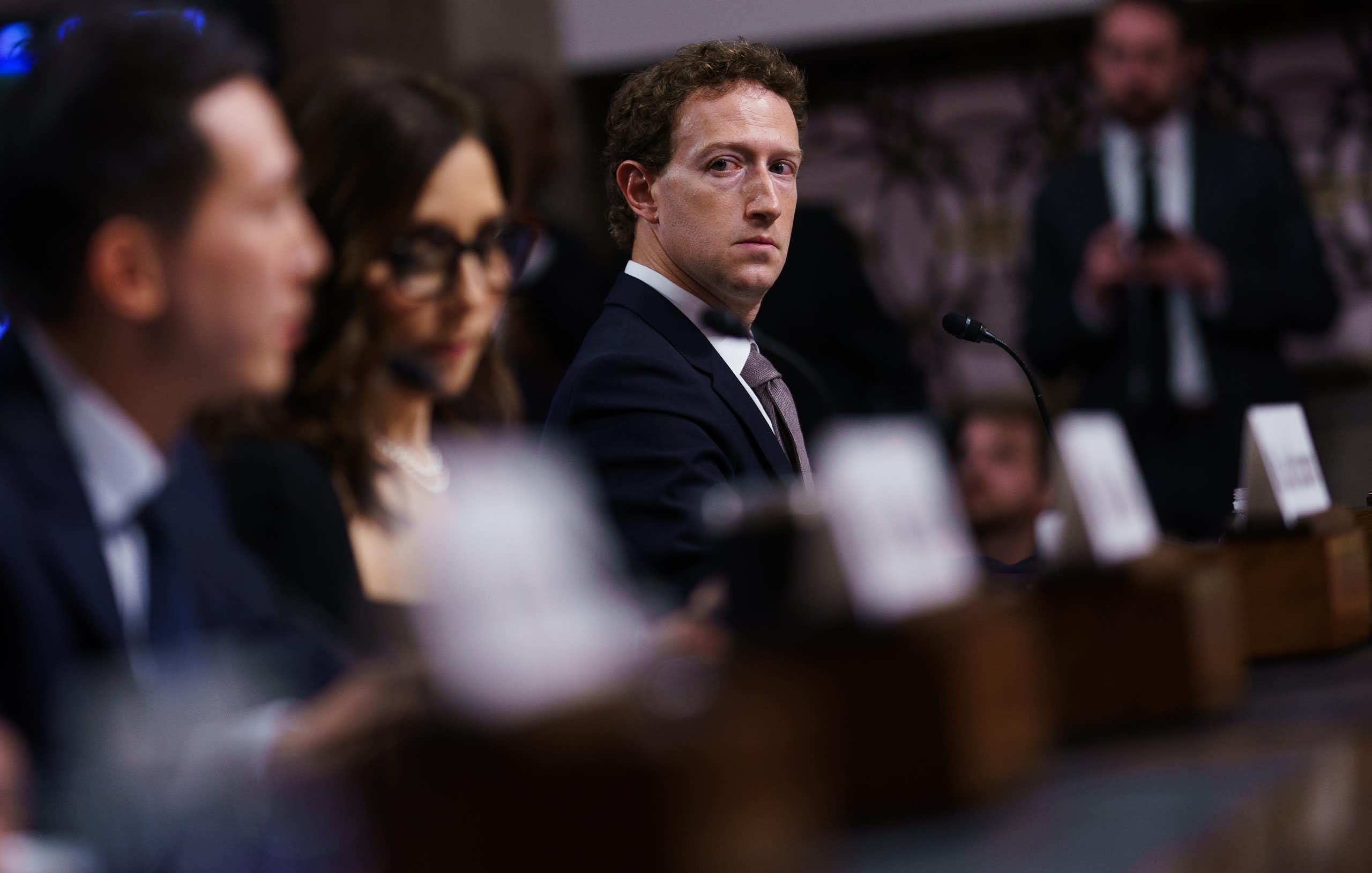 Mark zuckerberg looking solemn, sitting beside other tech executives in the Senate