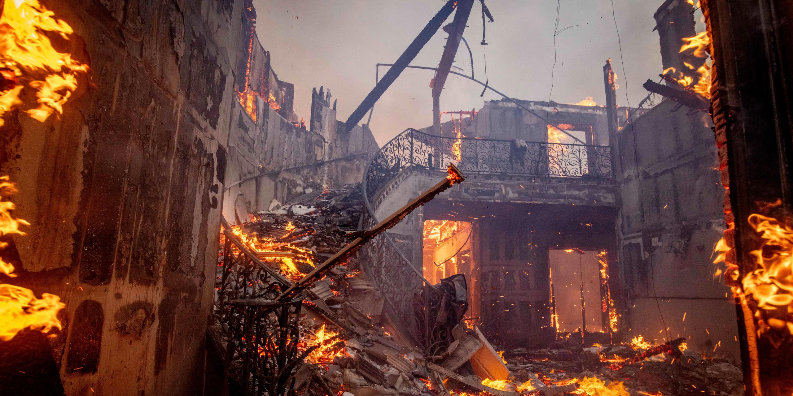 A burning home, with the central staircase still standing.