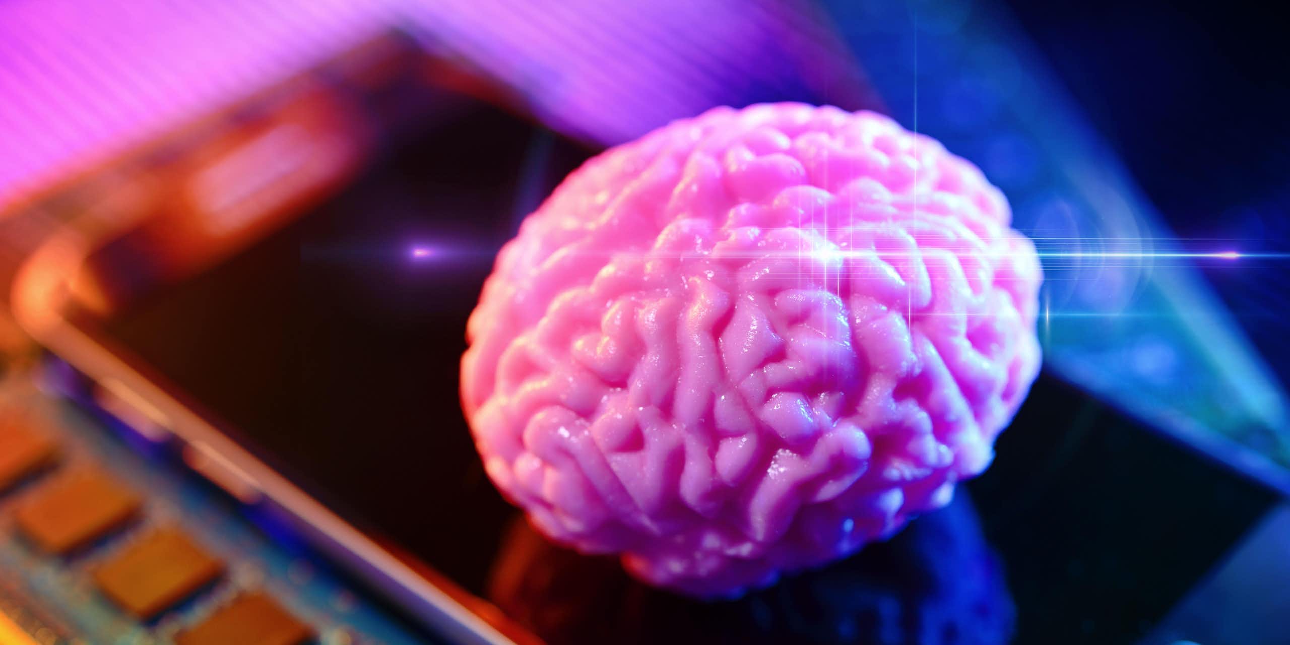 A pink brain on a smartphone with computer board.