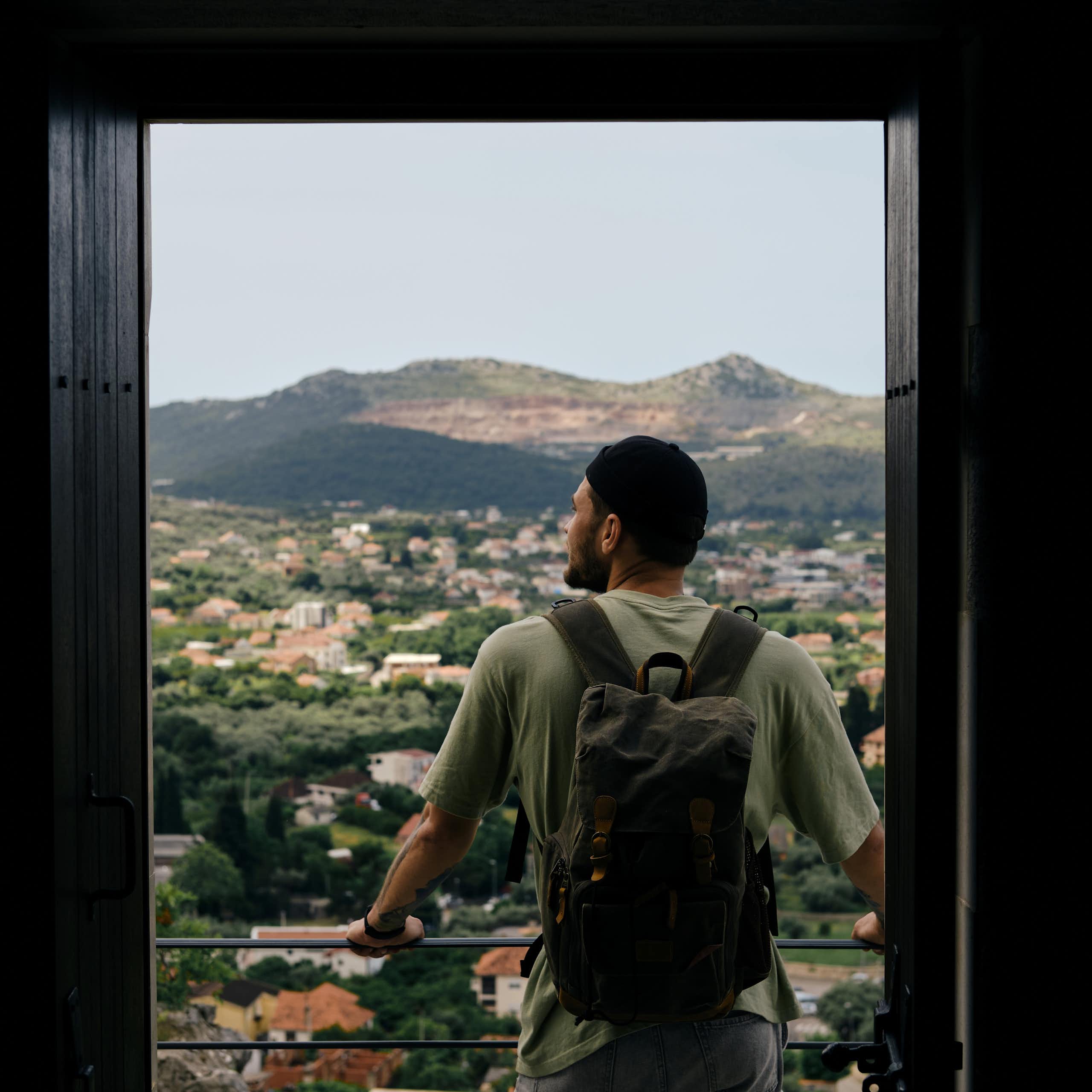 Man standing on balcony alone looking at a landscape