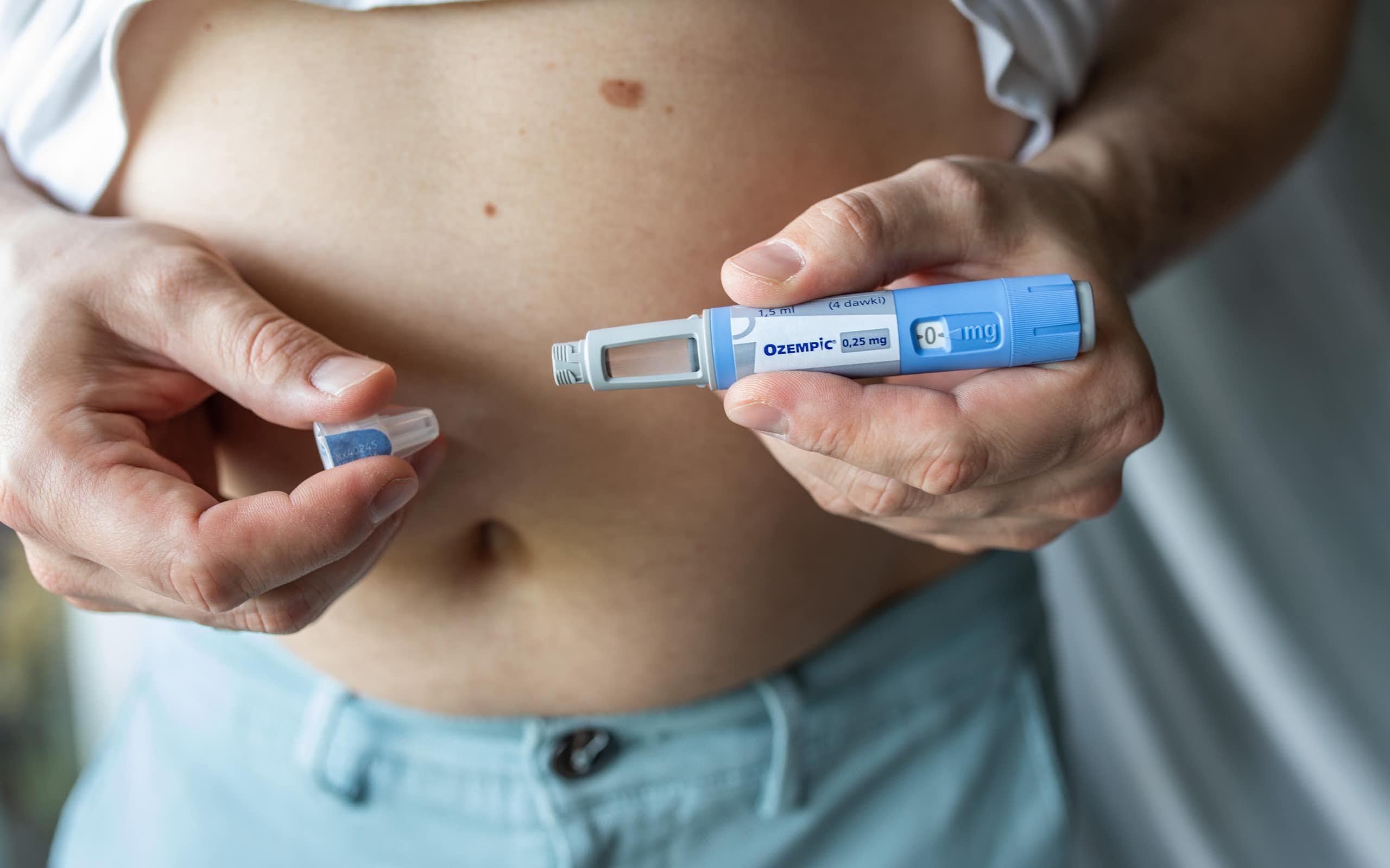 A person holds an Ozempic pen in front of their chest