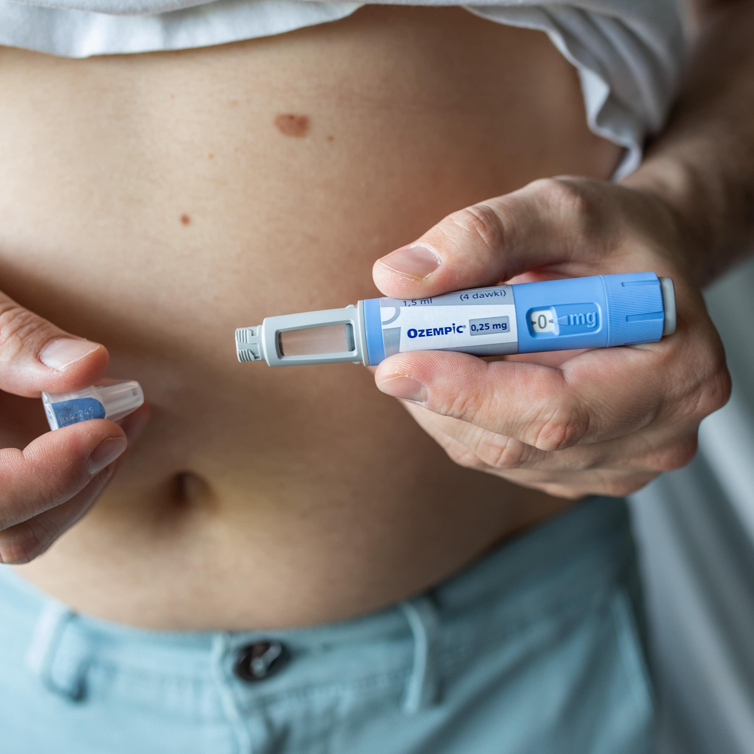 A person holds an Ozempic pen in front of their chest