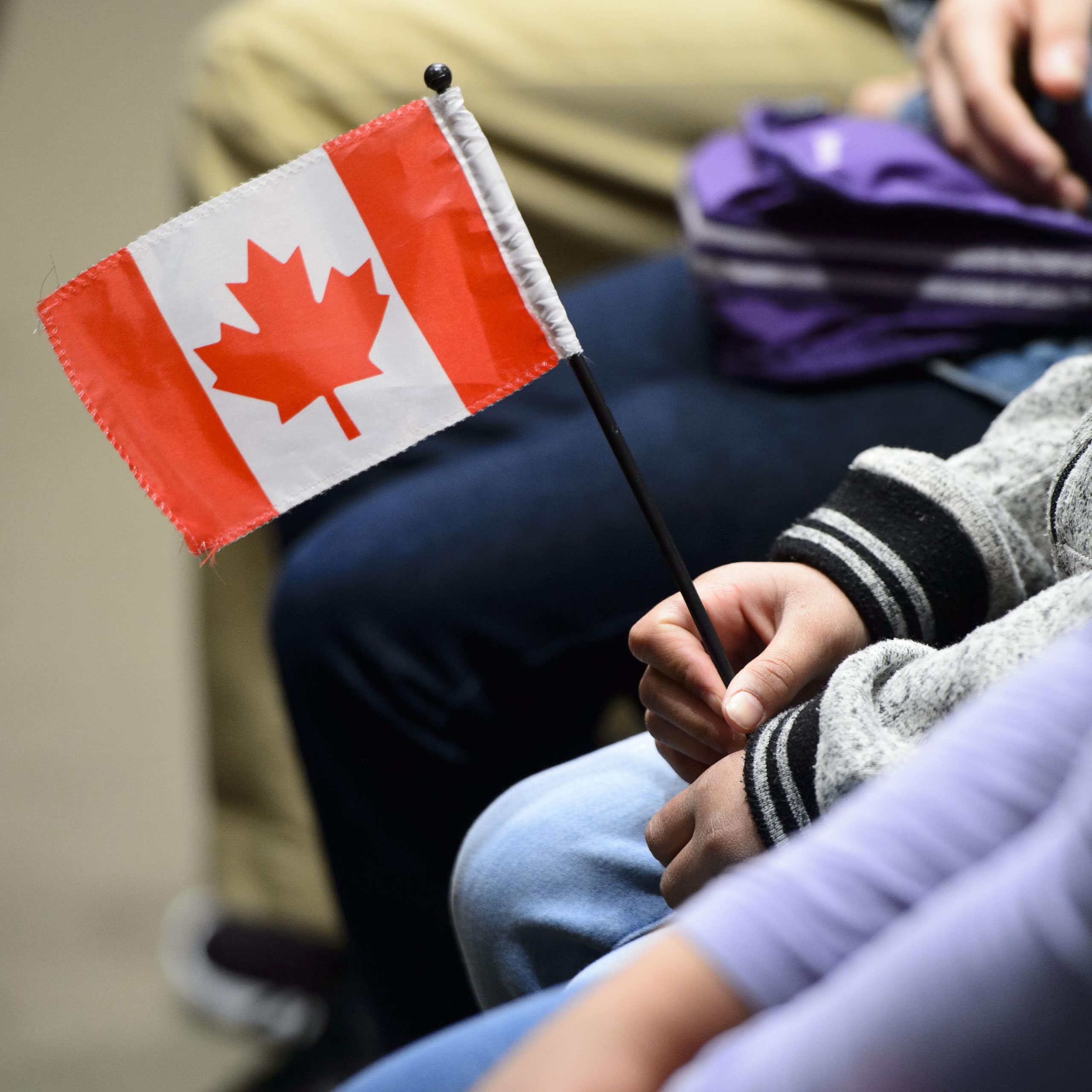 A Canadian flag is held in a person's hand.