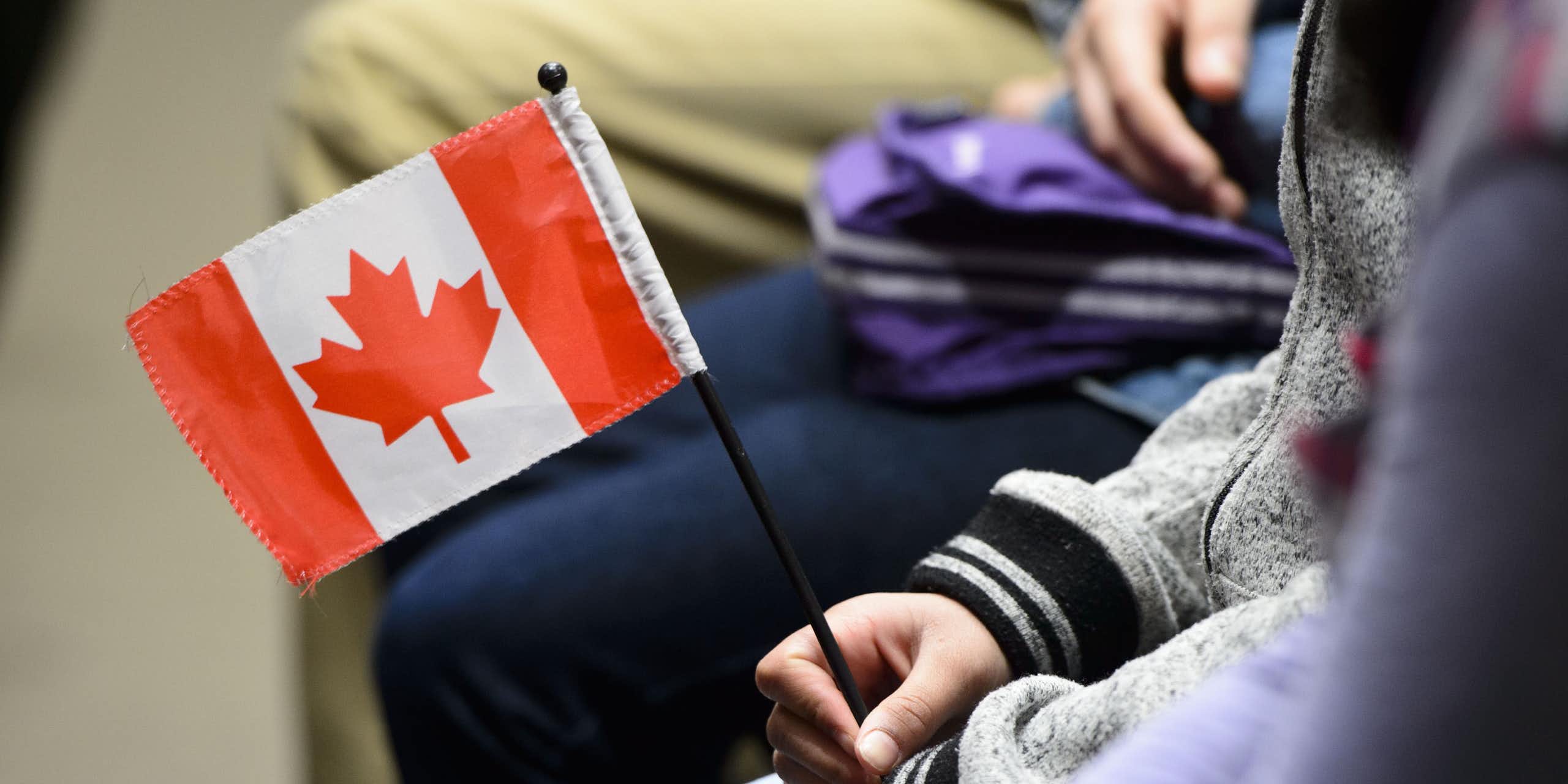 A Canadian flag is held in a person's hand.
