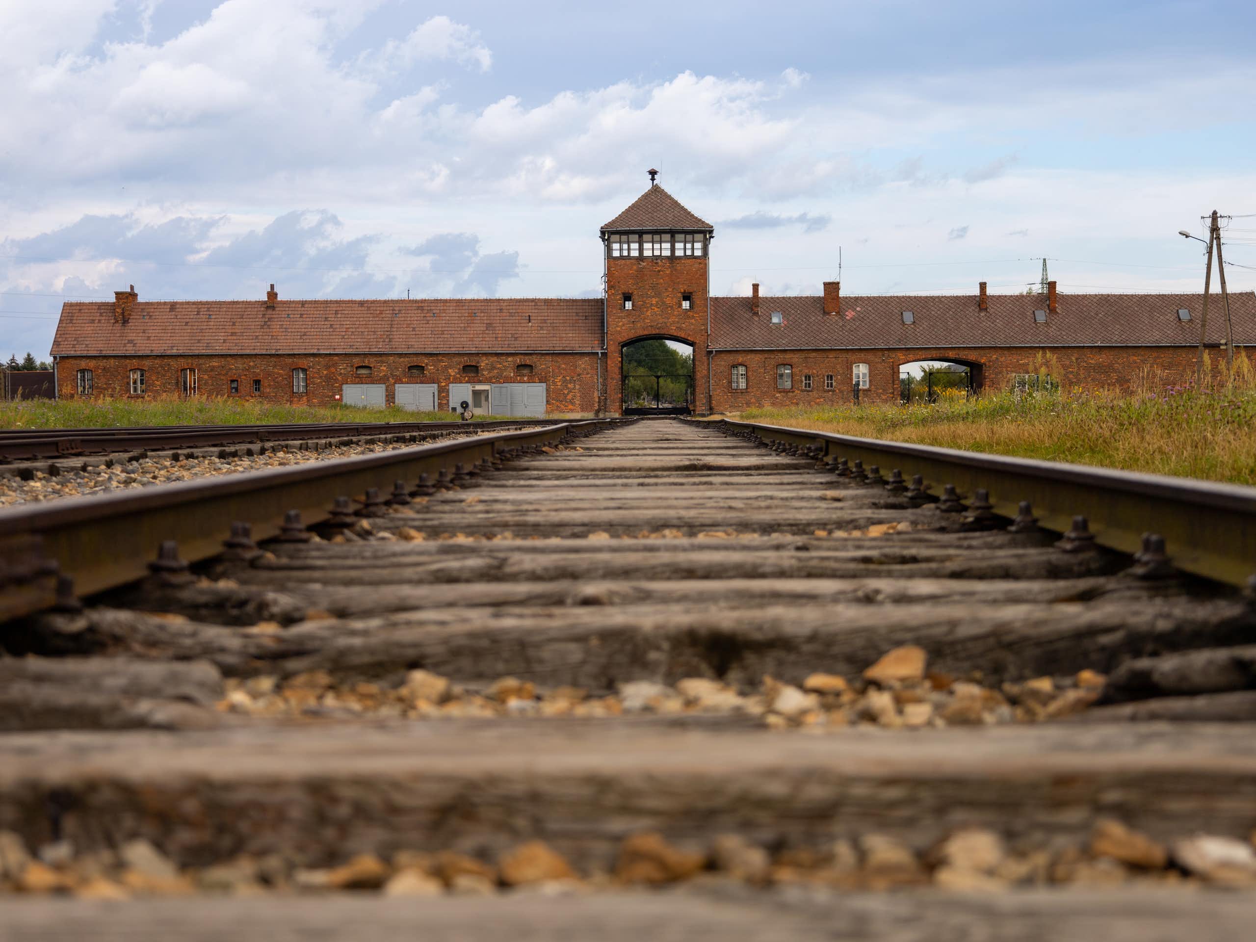 View of a disused railroad track, leading to a brick building.