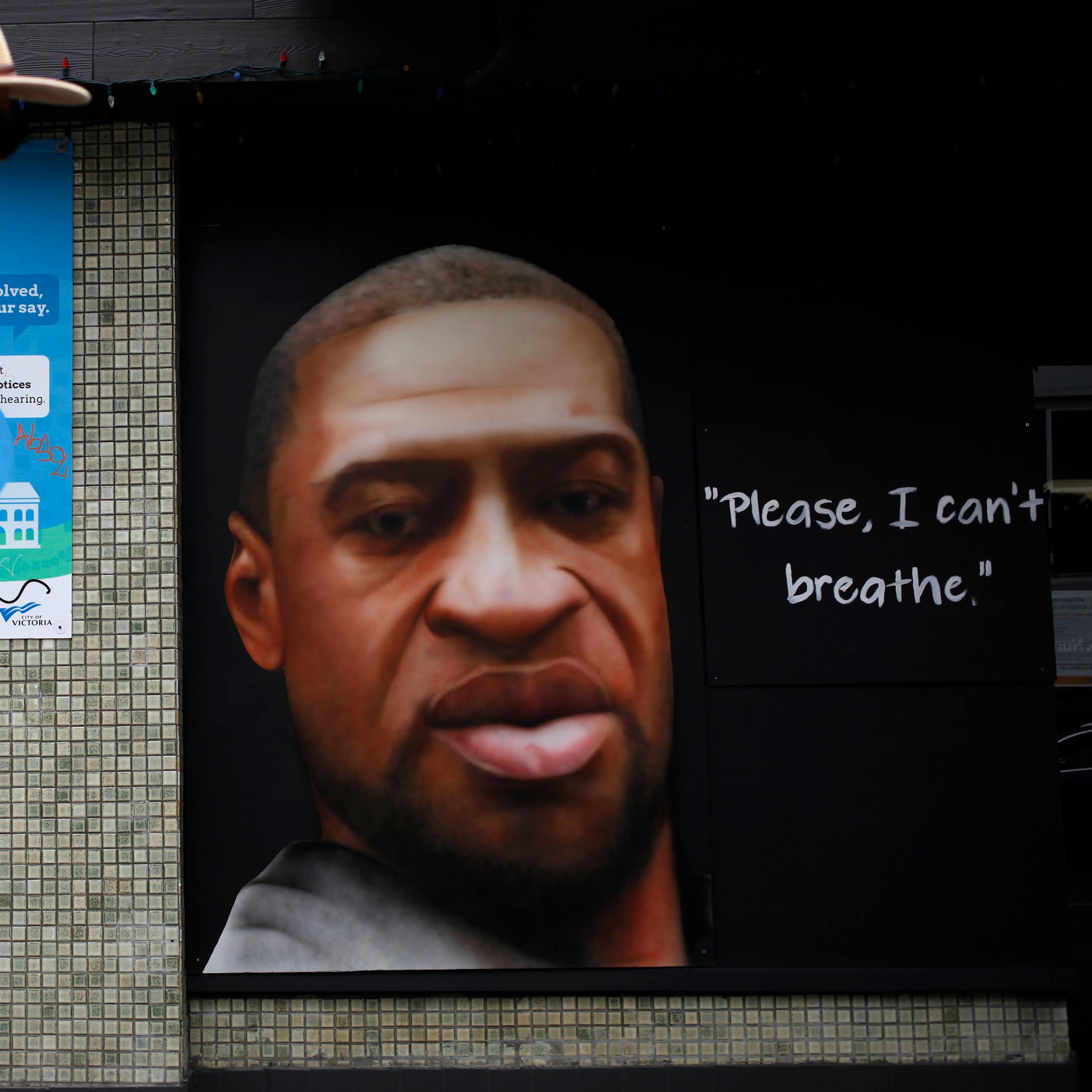 A mural depicts a man's face next to the quote 'please I can't breathe.'
