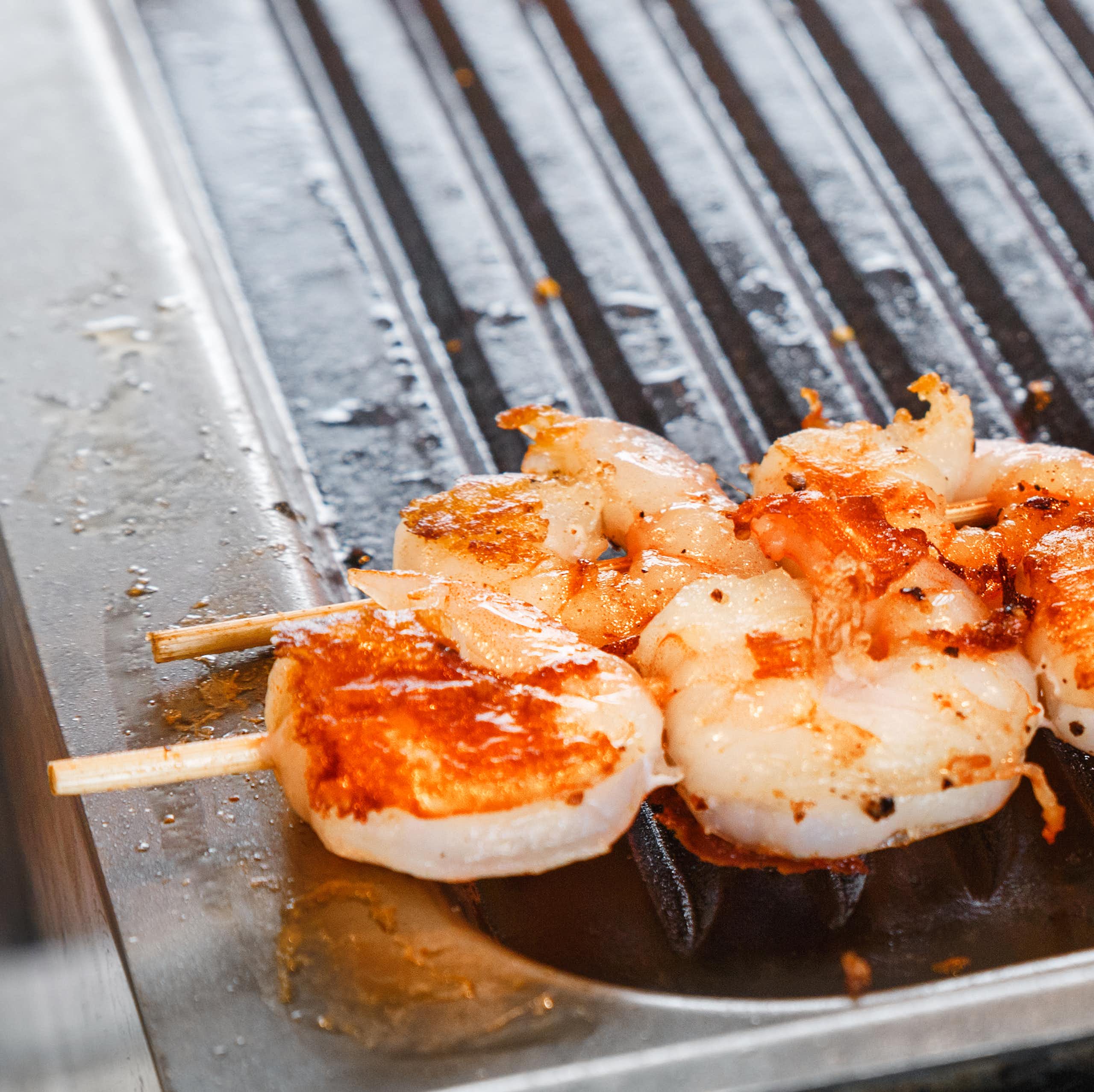 A skewer of prawns on a barbecue.
