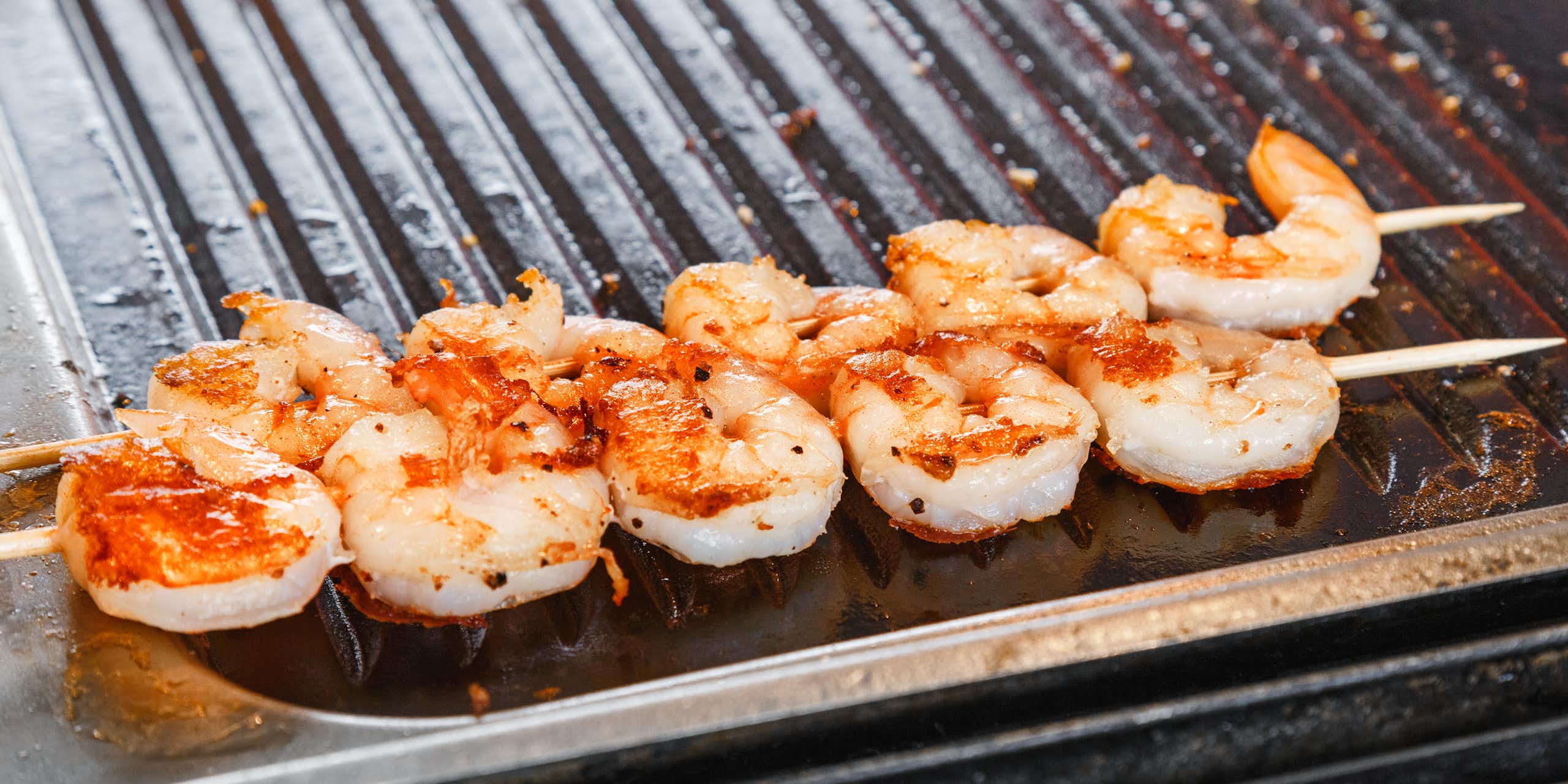 A skewer of prawns on a barbecue.