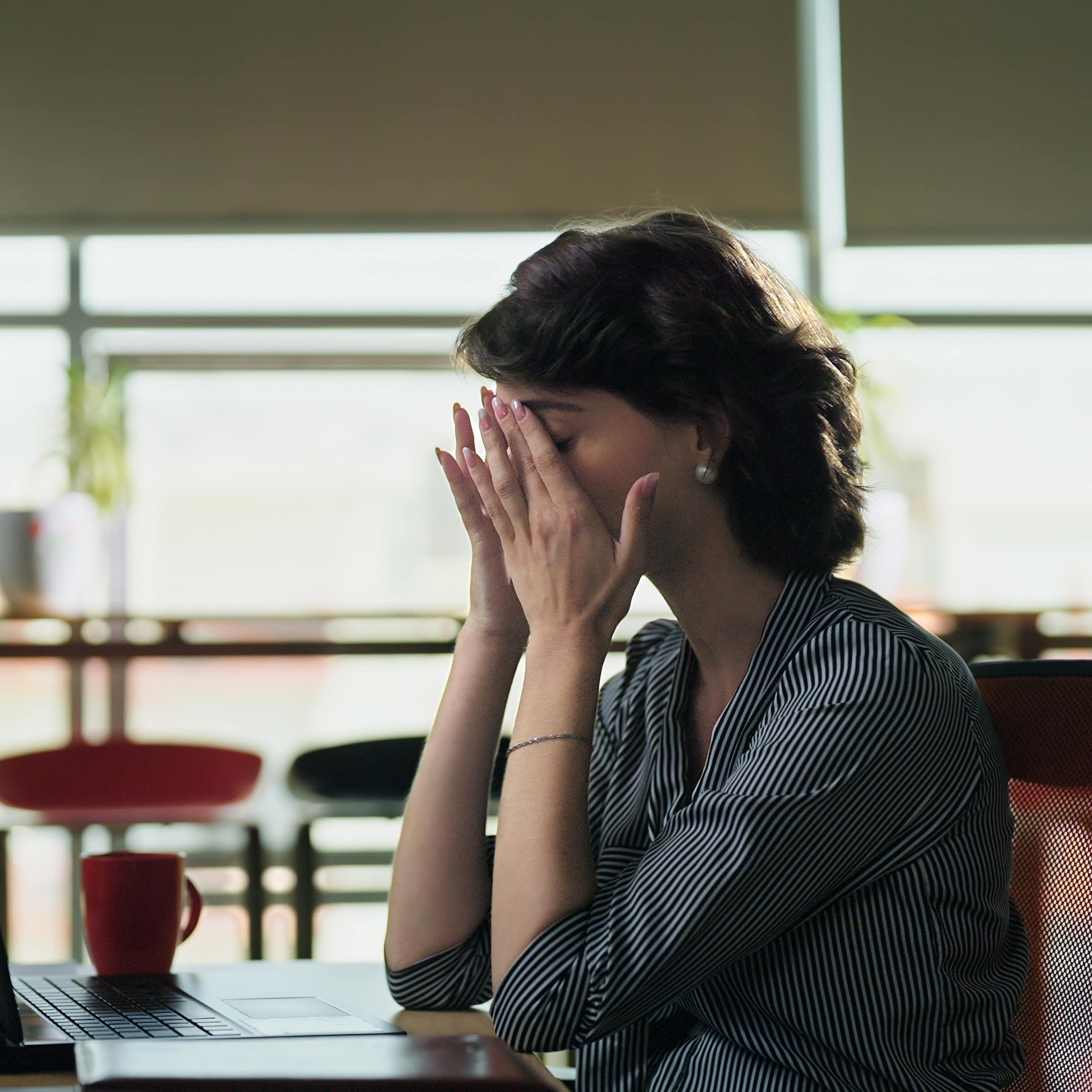 Woman sitting at desk rubbing her eyes