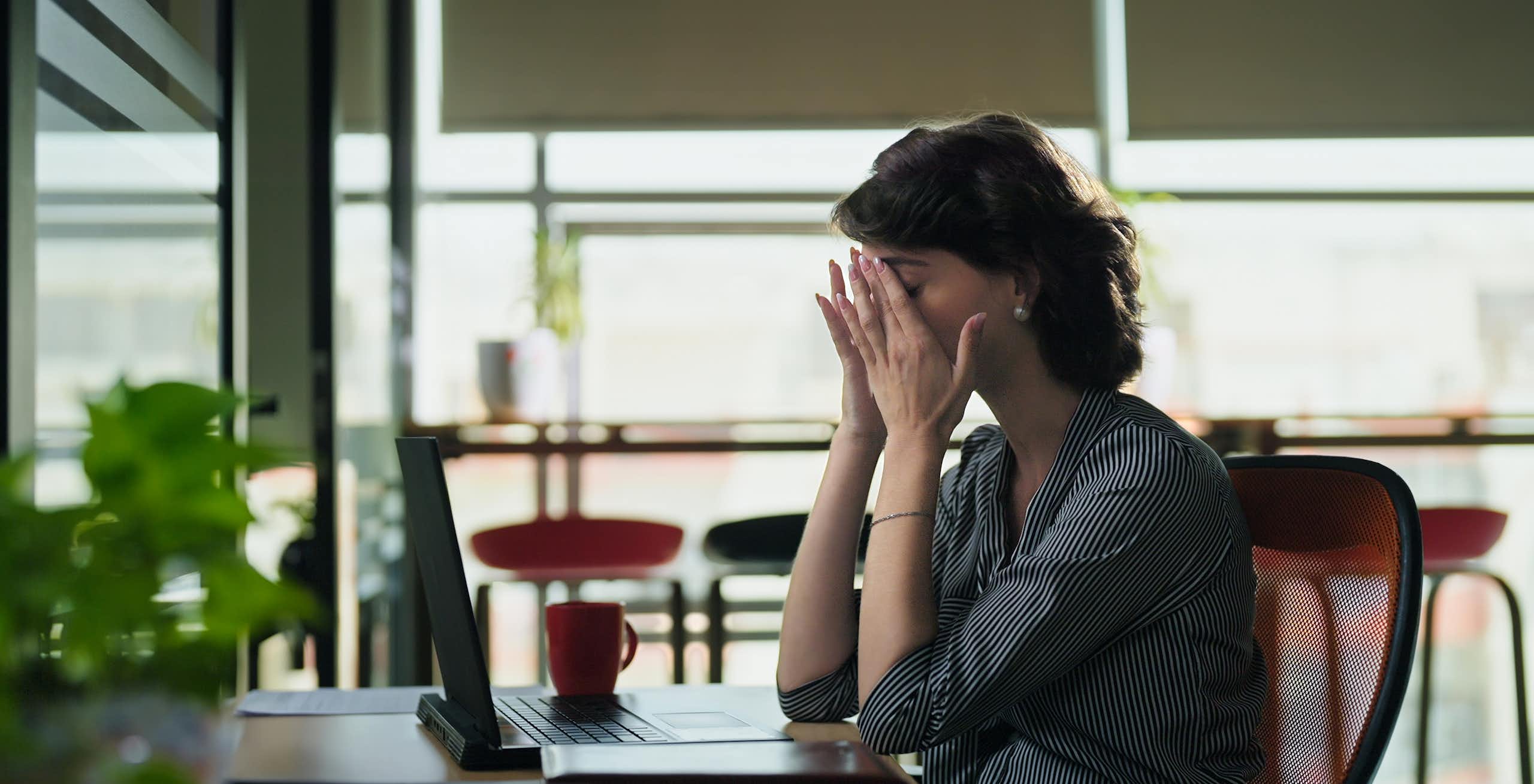 Woman sitting at desk rubbing her eyes