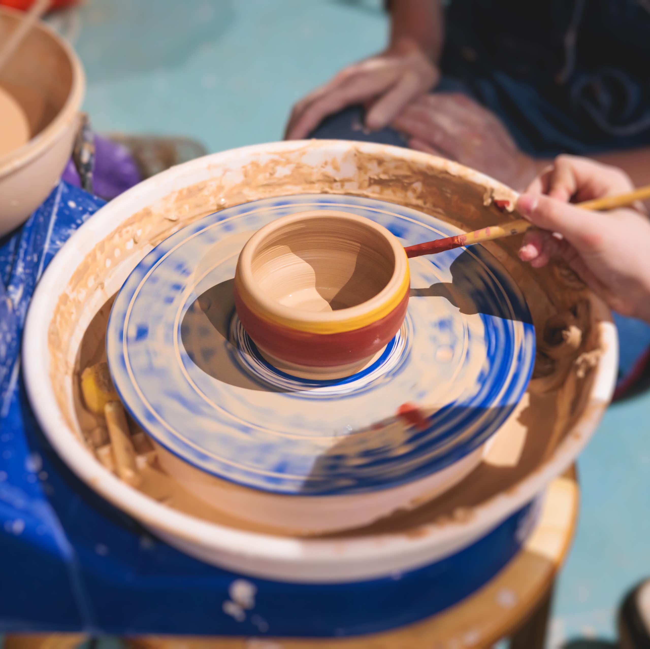 Person paints pottery on a pottery wheel