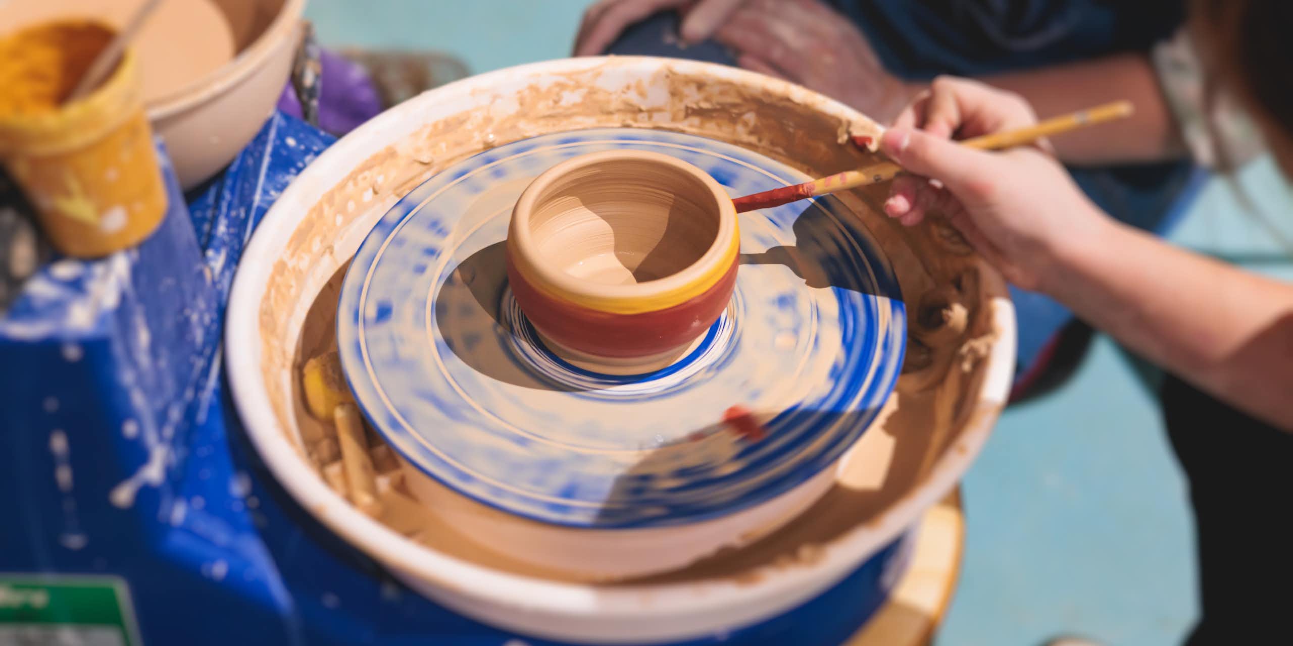 Person paints pottery on a pottery wheel
