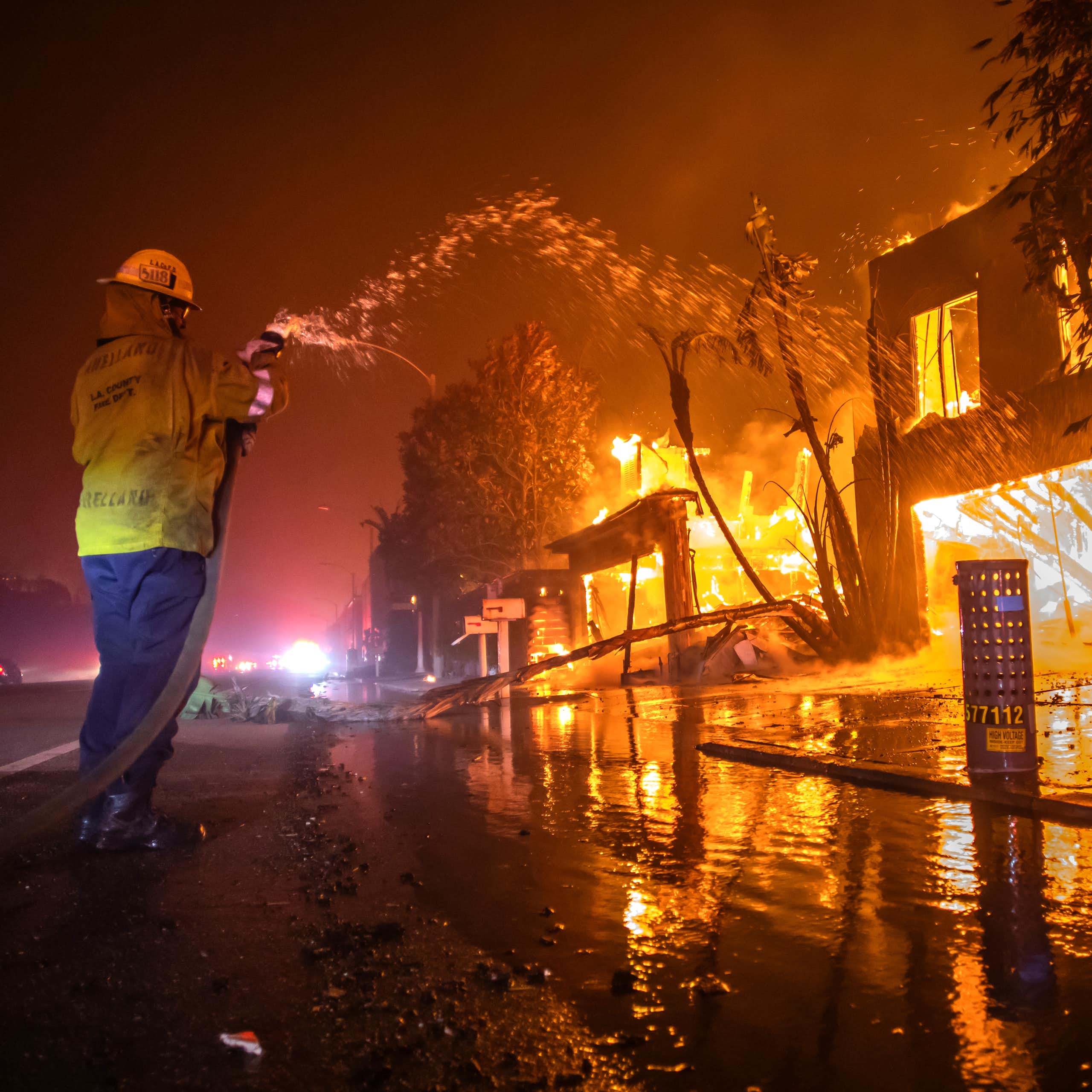 A firefighter battles the Palisades Fire while it burns homes at Pacific Coast Highway.