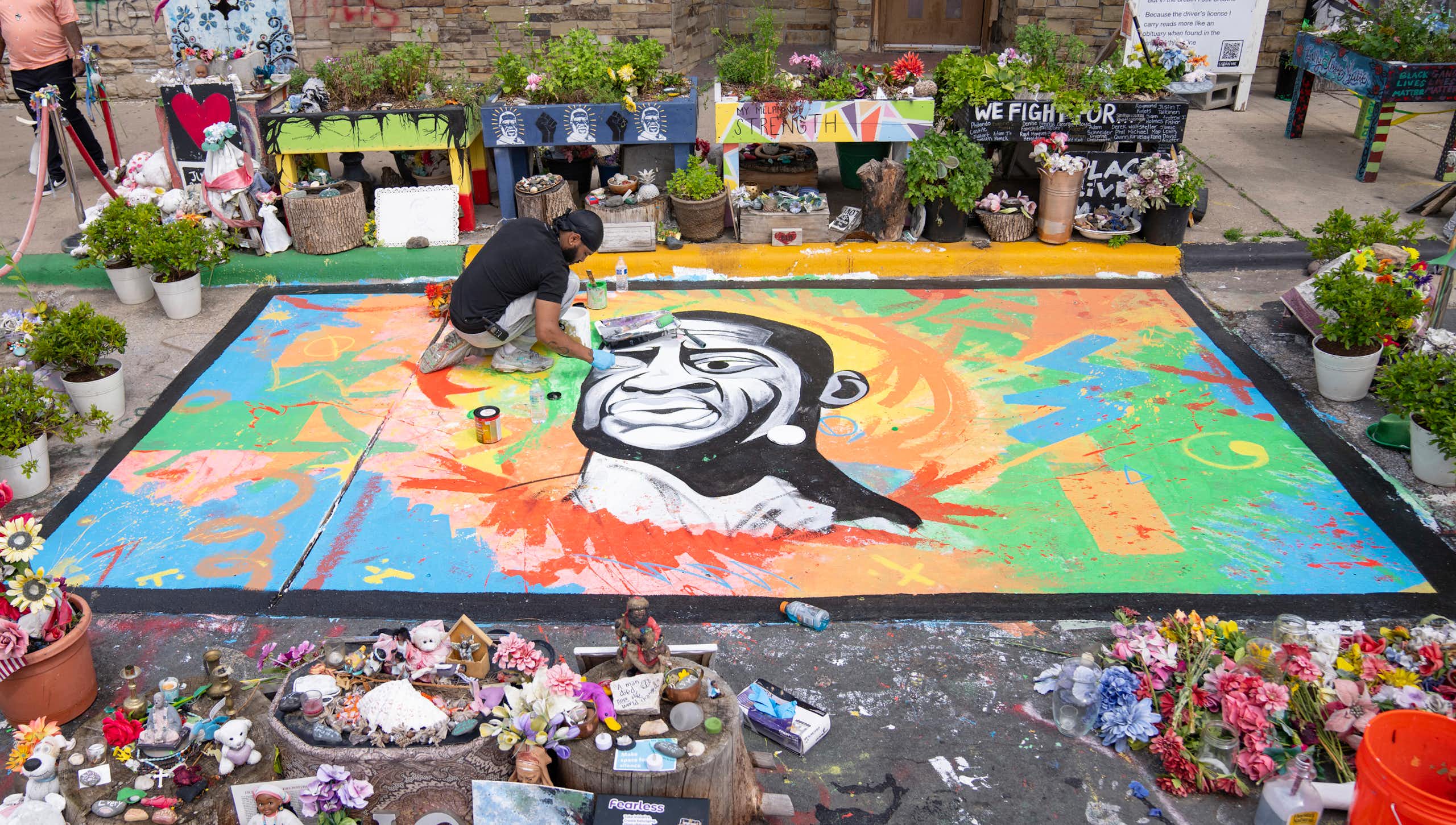 An artist working on a street mural of George Floyd