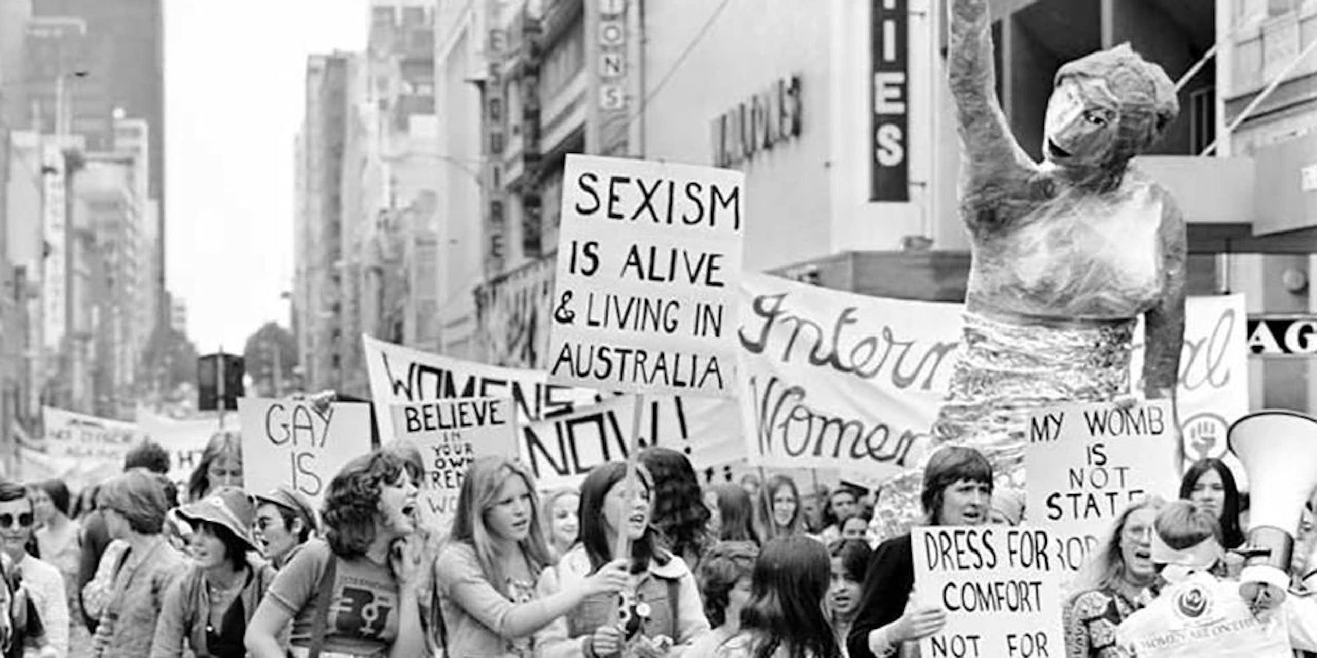 Historic black-and-white photo of women with placards marching against sexism