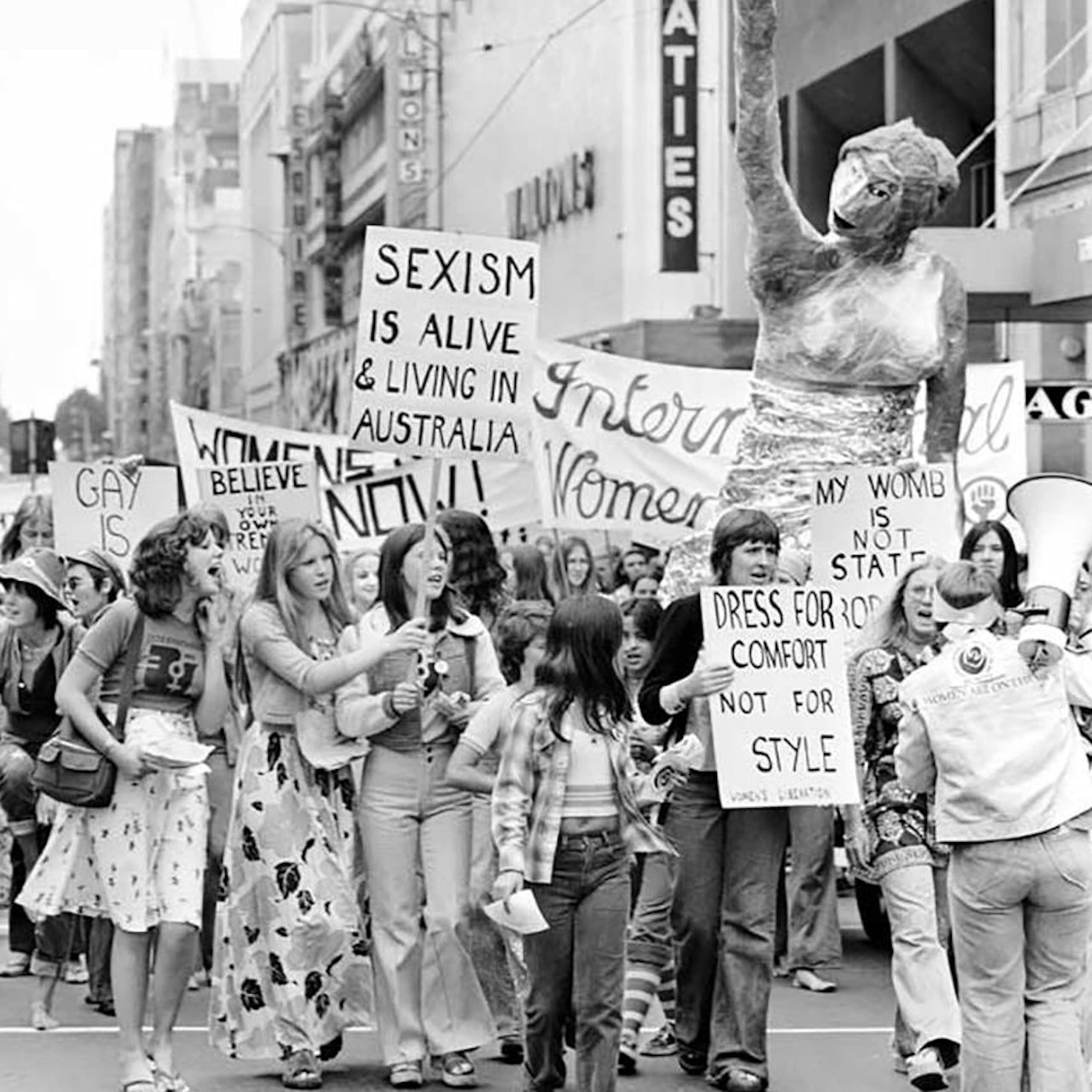 Historic black-and-white photo of women with placards marching against sexism
