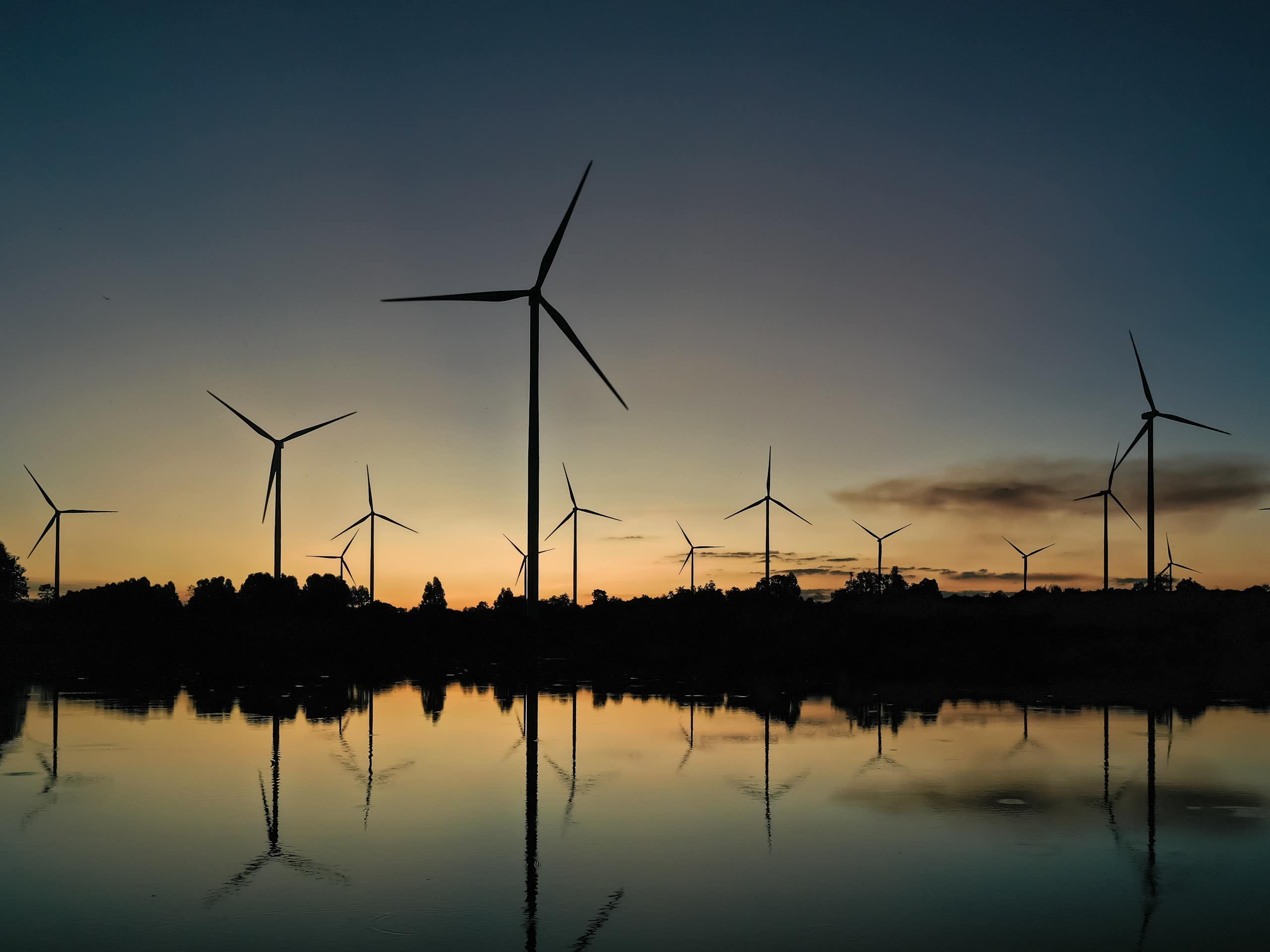 wind turbines reflected in water at dusk