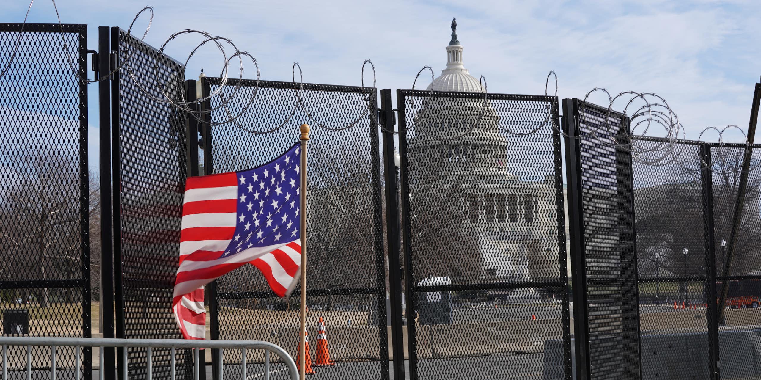 US capitol behind a fence with US flag in foreground.