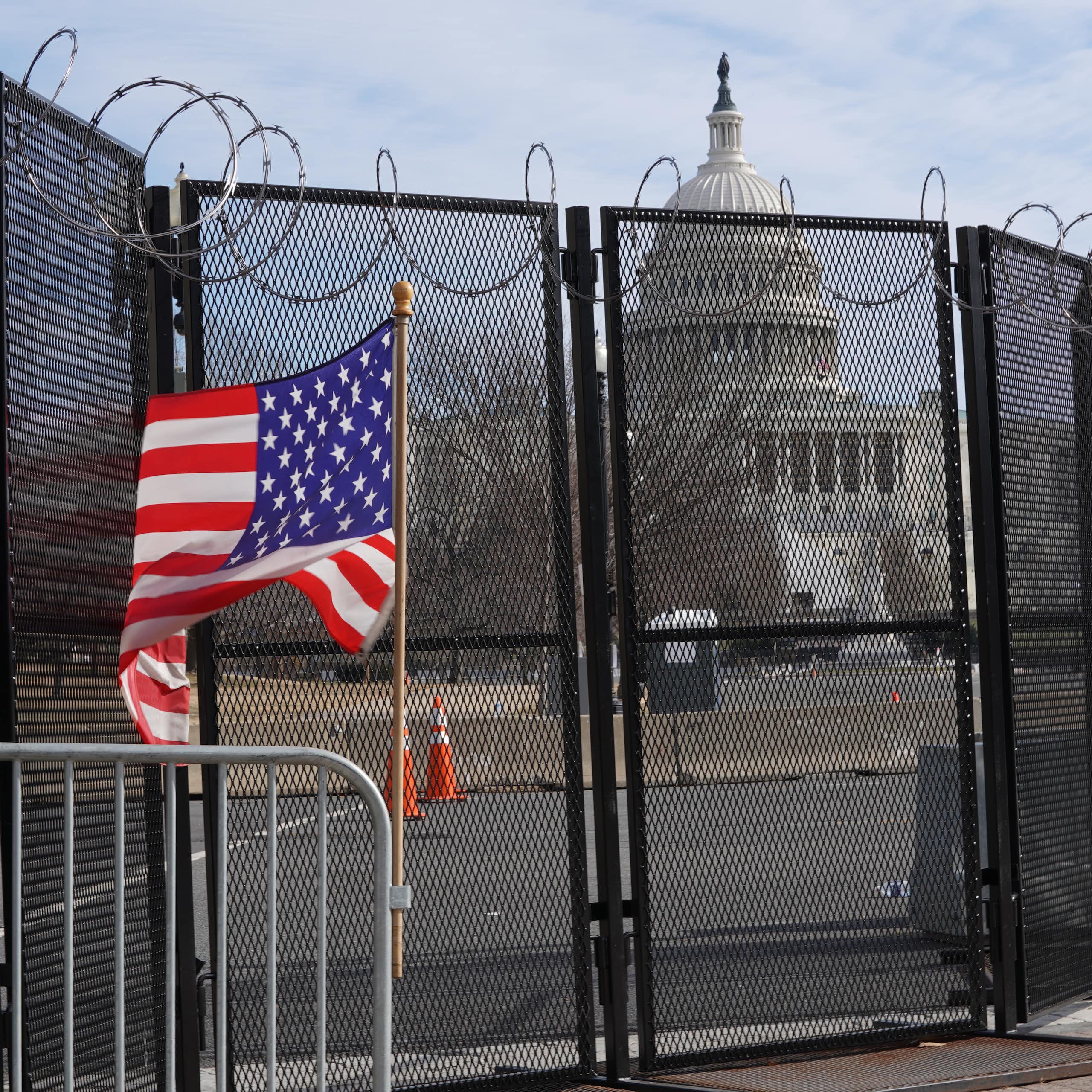 US capitol behind a fence with US flag in foreground.