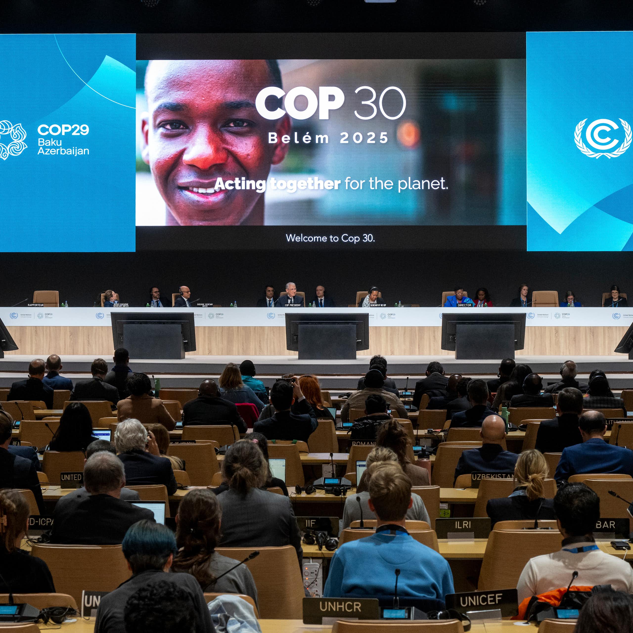 projected sign for COP30 and rows of delegates