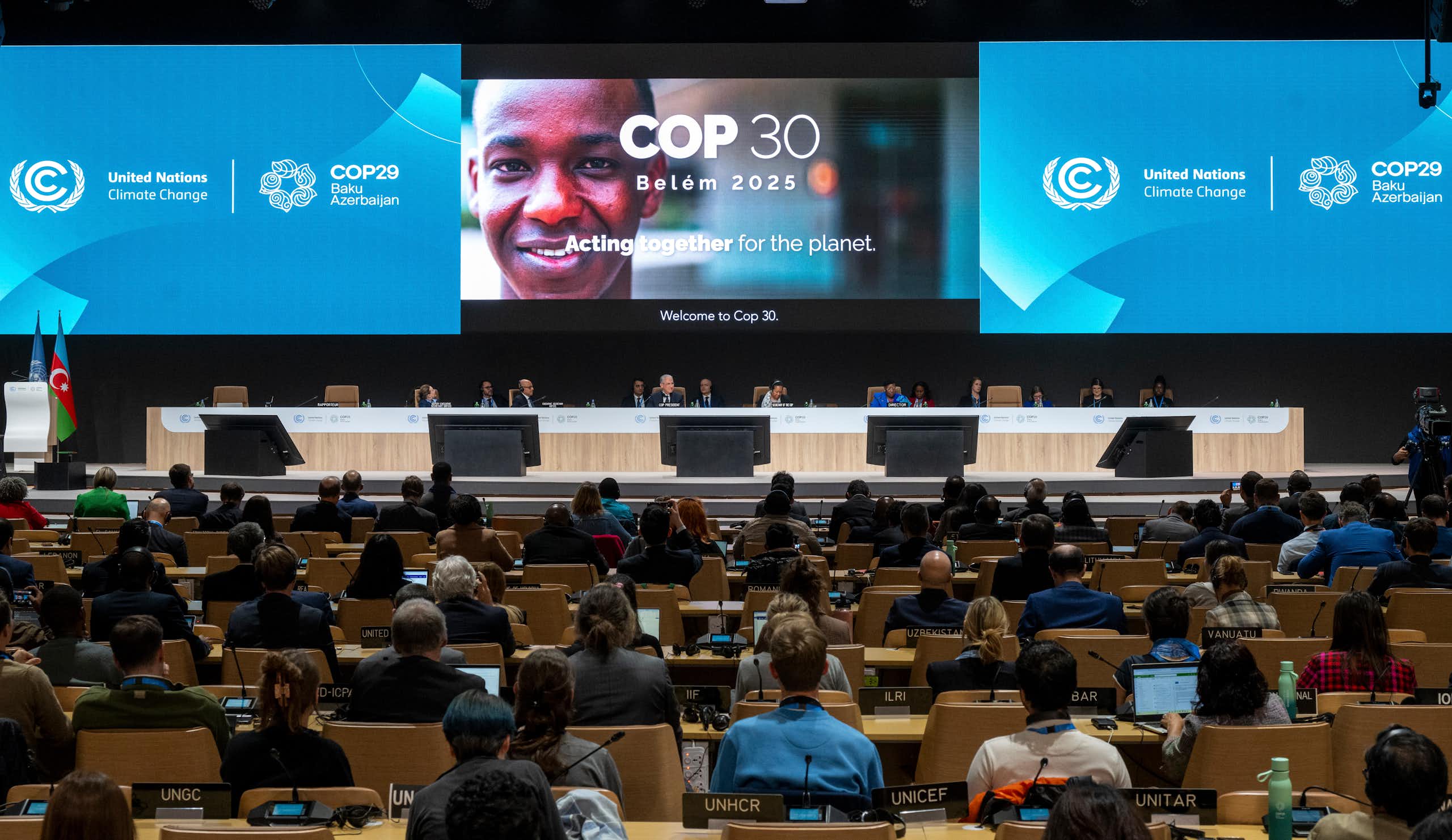 projected sign for COP30 and rows of delegates
