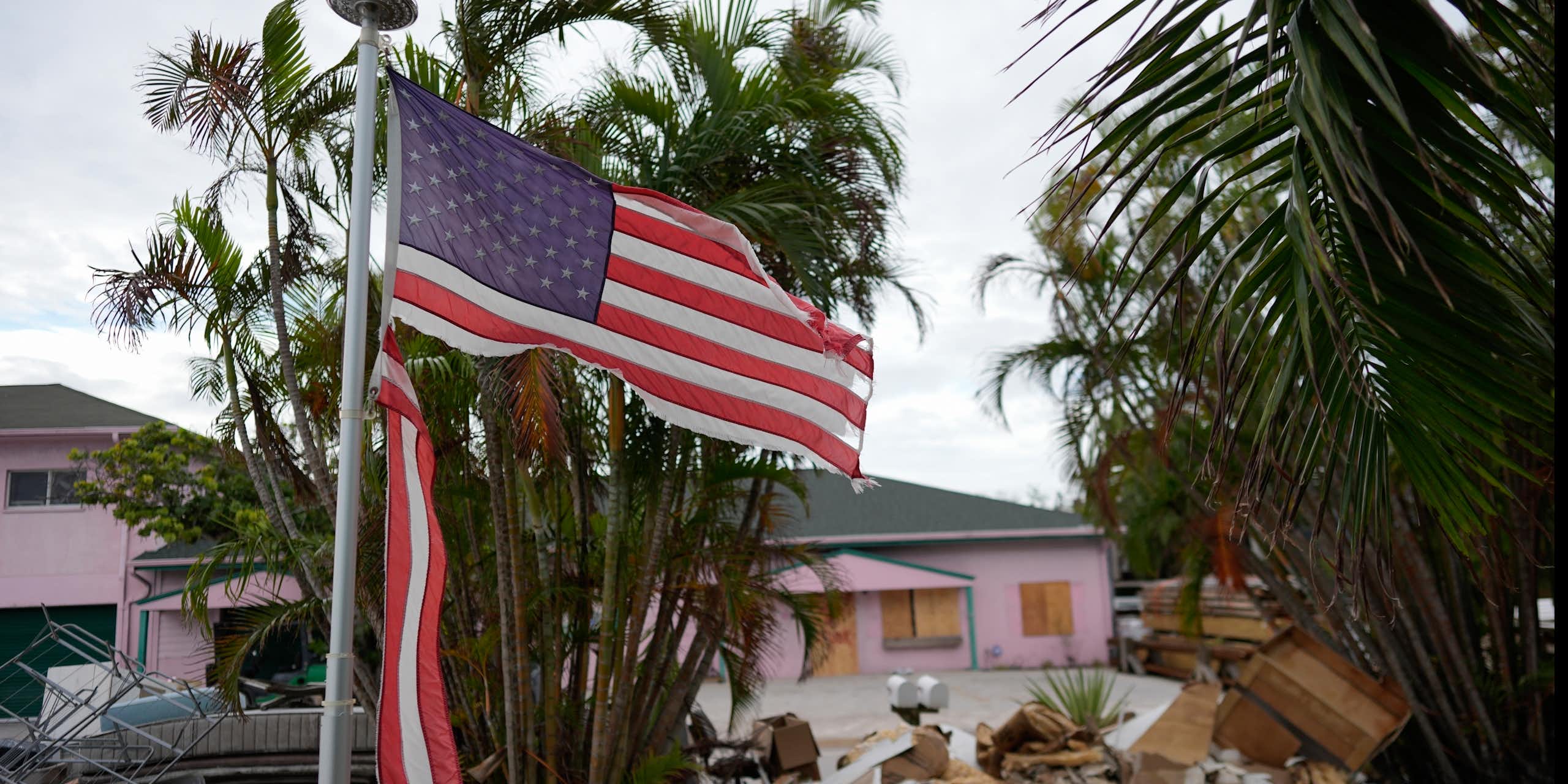 a tattered American flag flaps outside a home with furniture and household items damaged