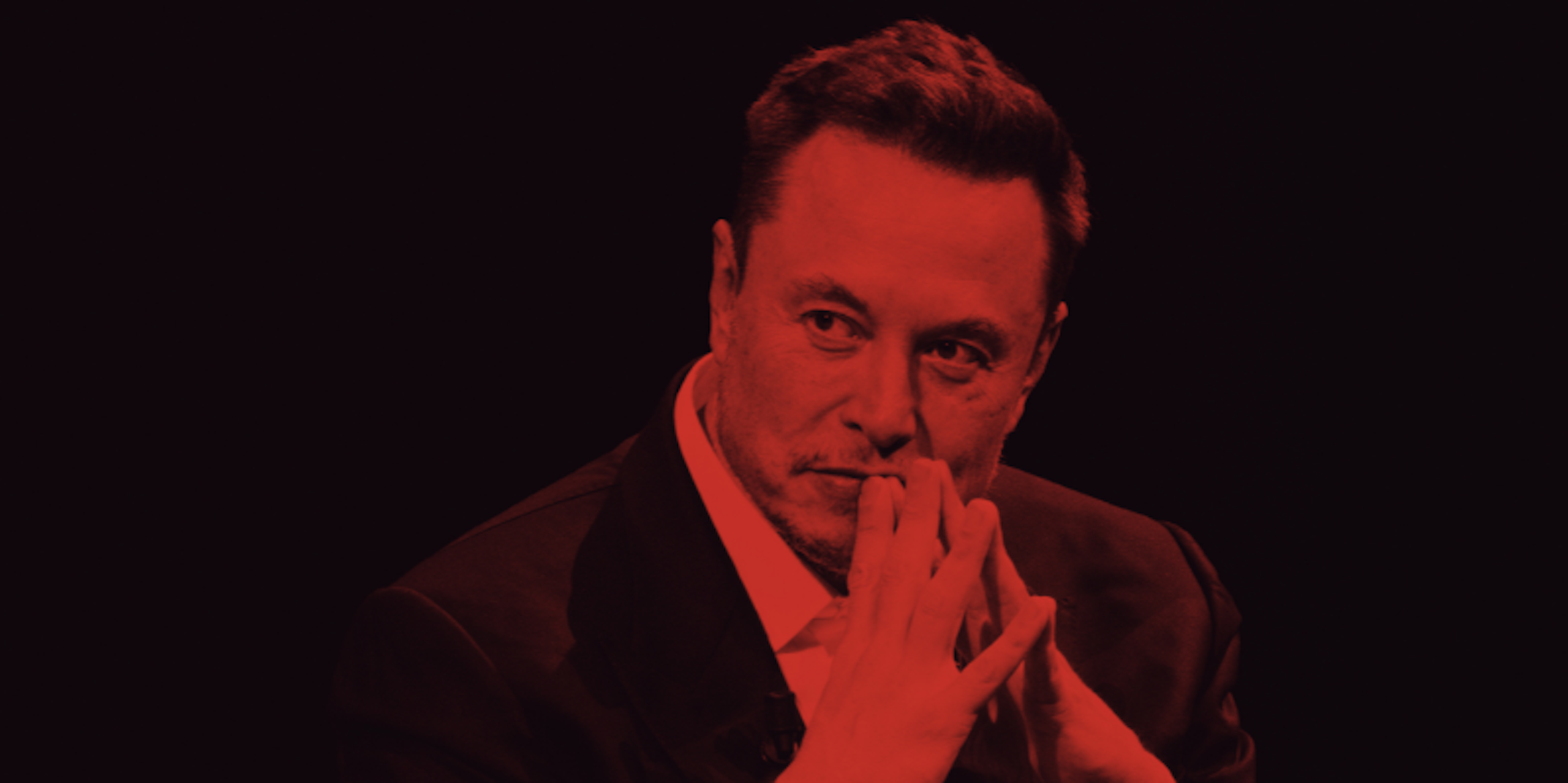 Elon Musk sits with his fingers together